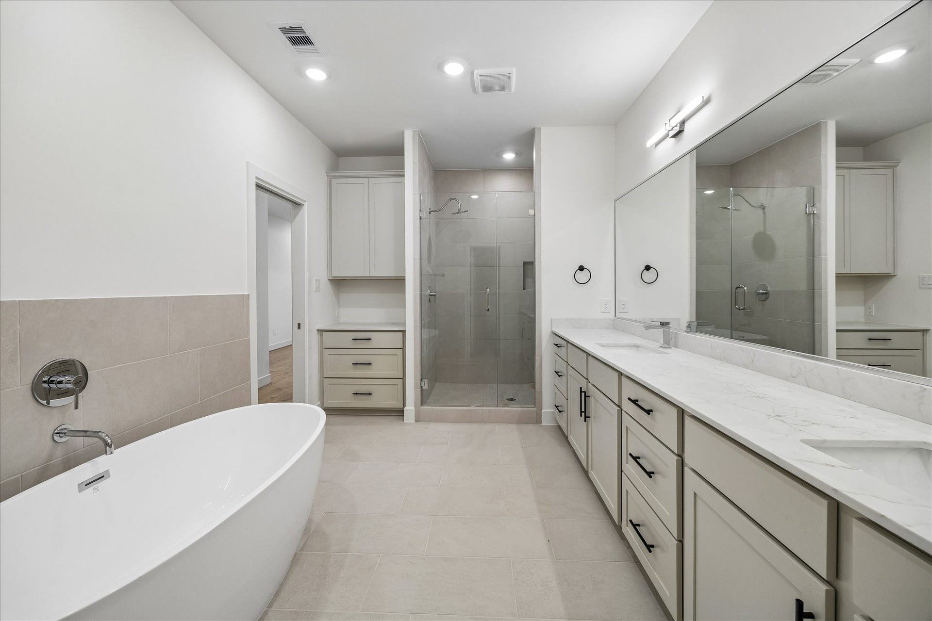 5018 Schuler Street, Houston, TX 77007 Luxurious primary bathroom featuring a freestanding soaking tub, glass-enclosed shower, dual vanities, and a dedicated counter area perfect for a morning coffee station.