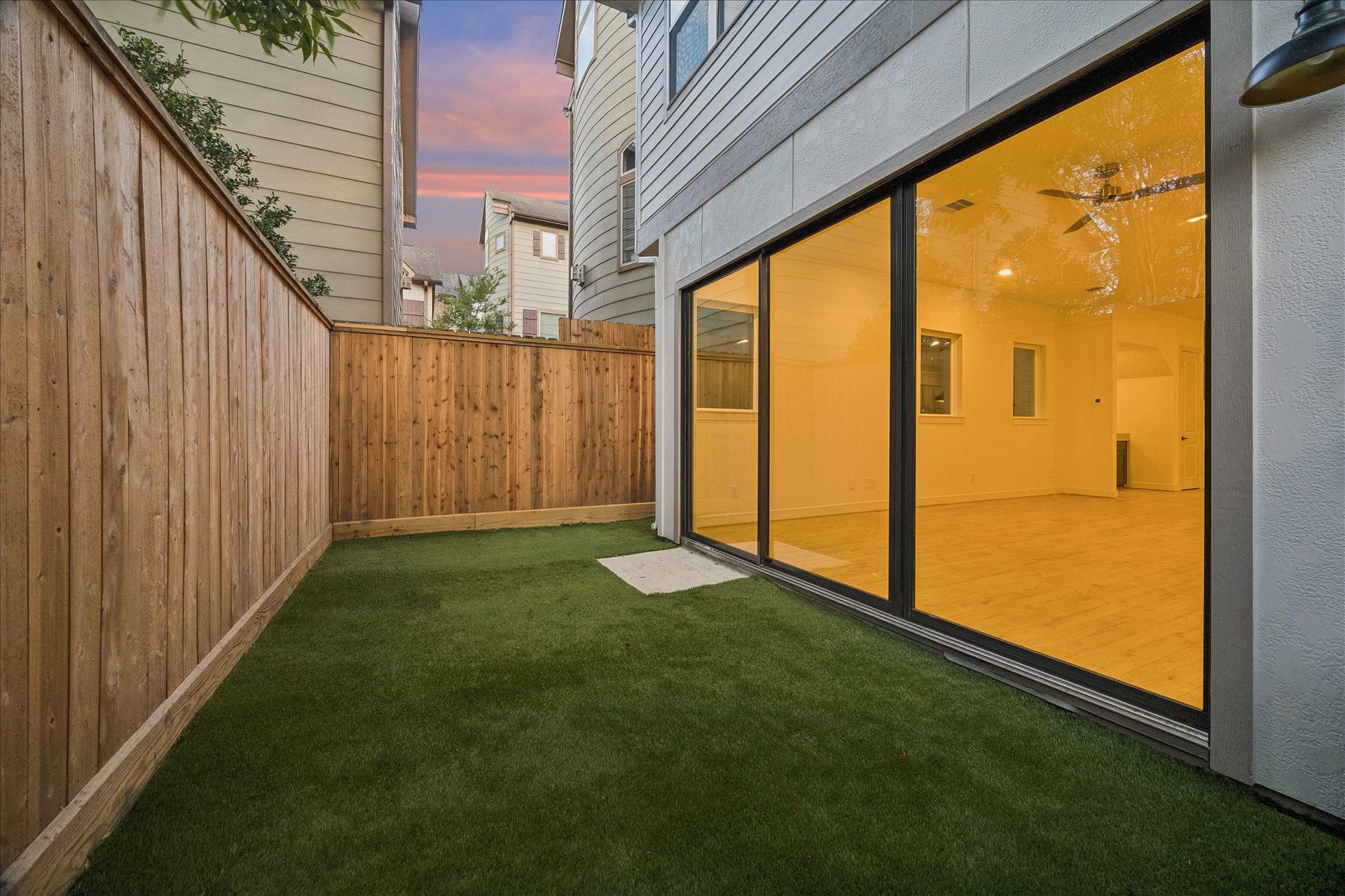 5018 Schuler Street, Houston, TX 77007 Private, fully fenced backyard featuring low-maintenance artificial turf and large sliding glass doors connecting seamlessly to the living area.