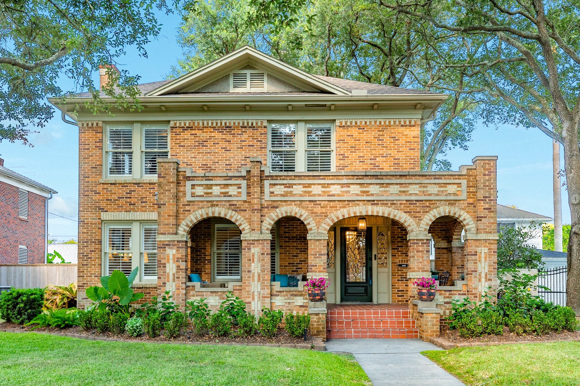 20 Cedar Lawn Drive S, Galveston, TX 77551 Front Exterior Historic 1935 American Foursquare with striking brick and stone archway details, framed by mature oak trees.