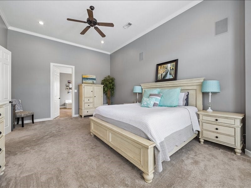 9007 Avebury Stone Circle, Missouri City, TX 77459 The primary suite's beautifully furnished king bedroom showcases a panel-style bed frame, matching nightstands with coastal teal lamps, and direct access to the en suite bath.
