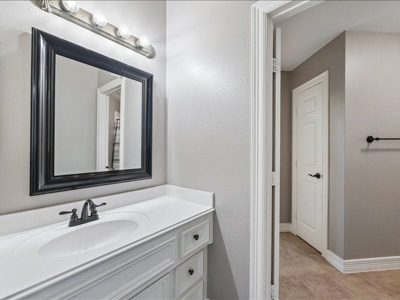 9007 Avebury Stone Circle, Missouri City, TX 77459 The secondary bath's split configuration provides a second dedicated vanity area with matching white cabinetry and black-framed mirror, and ideal set up for shared use by children, guests or family members.