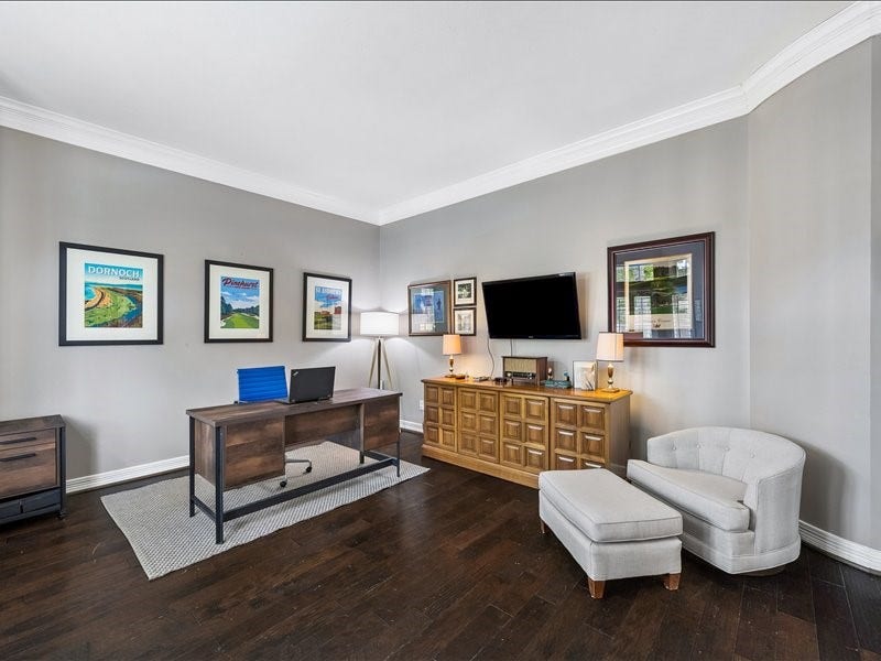 9007 Avebury Stone Circle, Missouri City, TX 77459 A sophisticated home office off the entry foyer featuring hardwood floors, crown molding, a large desk, wall-mounted TV, and a credenza, the ideal retreat for the work-from-home professional or a refined formal sitting room.