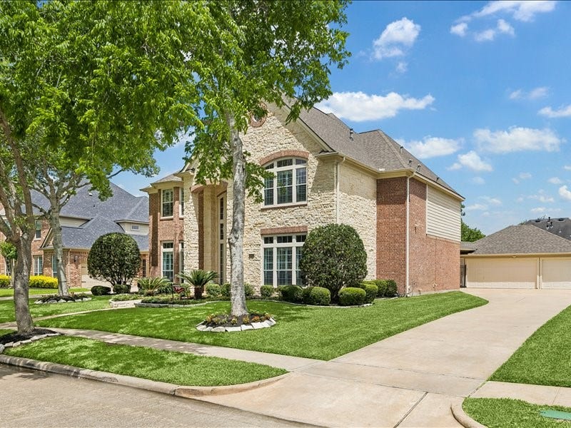 9007 Avebury Stone Circle, Missouri City, TX 77459 A closer street-angle view of the driveway, lawn and brick and stone exterior with classic shuttered windows.