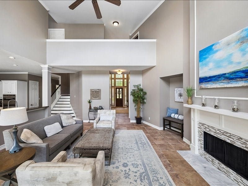 9007 Avebury Stone Circle, Missouri City, TX 77459 Wide-angle view capturing the seamless flow between the family room, entry foyer, and kitchen showcasing the open floor plan's generous proportions with soaring ceilings, large-spaced tile, and an abundance of natural light.