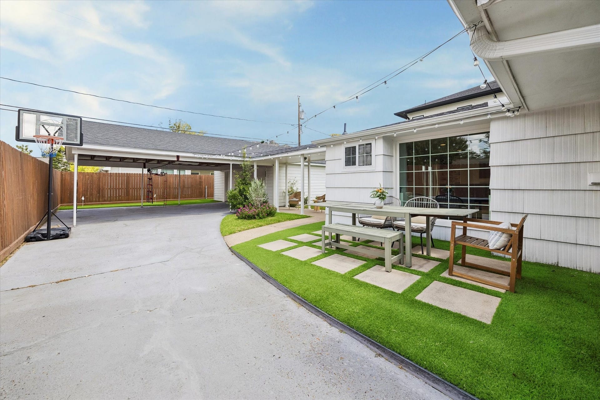 1232 Chantilly Lane, Houston, TX 77018 Low maintenance backyard with artificial turf and real grass, an outdoor dining area, string lights, and covered parking for added functionality.