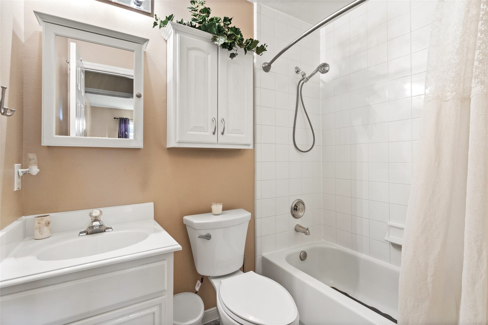 3001 Meadow Bay Drive, Dickinson, TX 77539 Charming bathroom featuring a classic white tub with a handheld shower, complemented by a sleek vanity, mirrored cabinet, and ample storage.