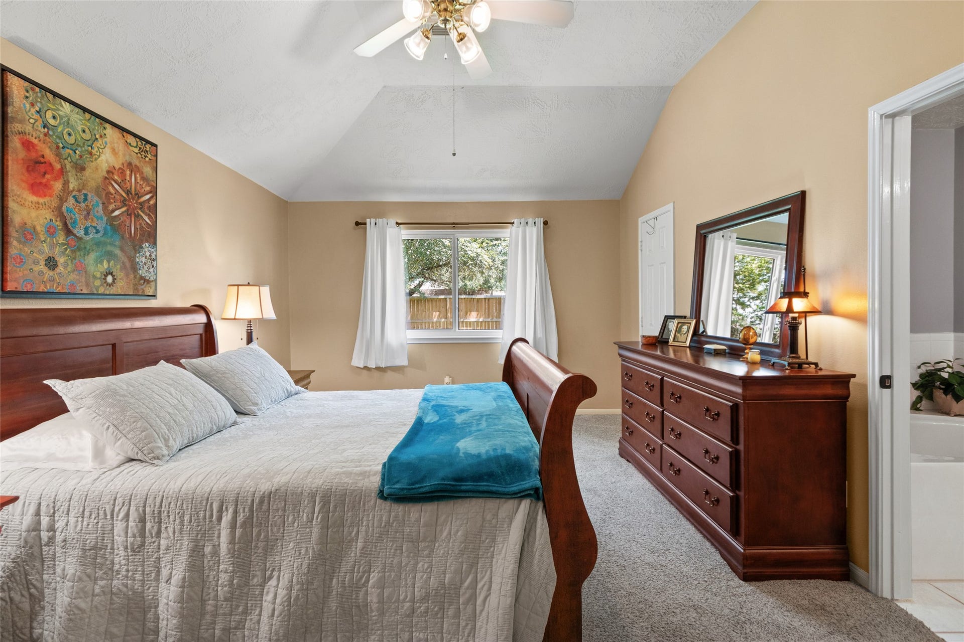 3001 Meadow Bay Drive, Dickinson, TX 77539 Spacious primary bedroom with a vaulted ceiling, ceiling fan, comfy carpet, and a large window offering plenty of natural light.