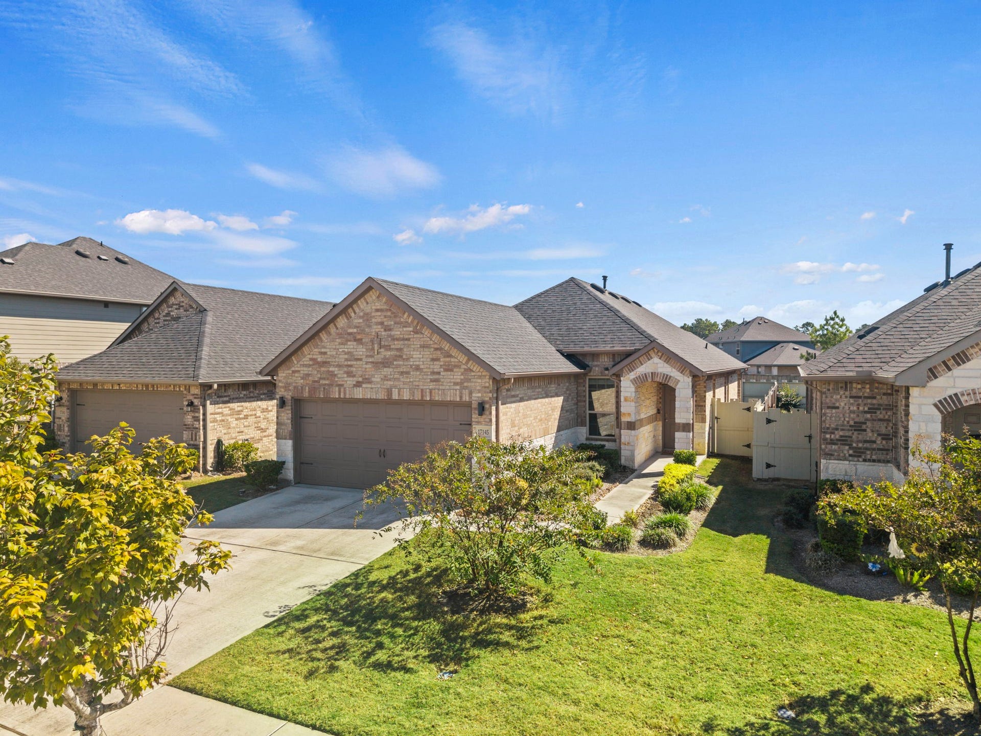 Charming single-story brick home featuring a welcoming covered entry, a two-car garage, and a landscaped front yard with a spacious driveway.