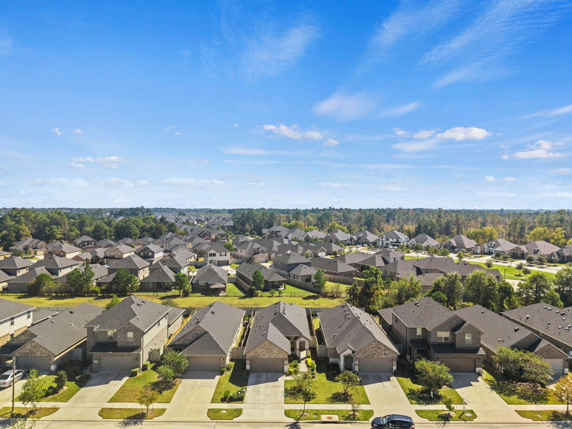 A birds-eye view showcasing the home's charming curb appeal, spacious driveway, and surrounding neighborhood.