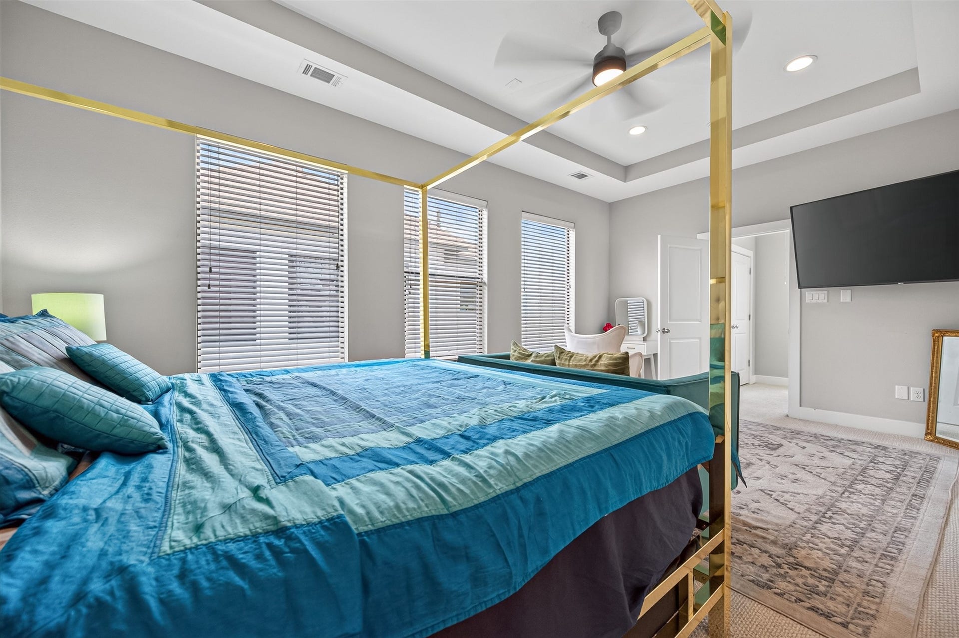 2805 Blodgett Street, #C, Houston, TX 77004 Spacious bedroom featuring a luxurious canopy bed, modern ceiling fan, and large windows for ample natural light, complemented by a sleek wall-mounted TV and cozy seating area.