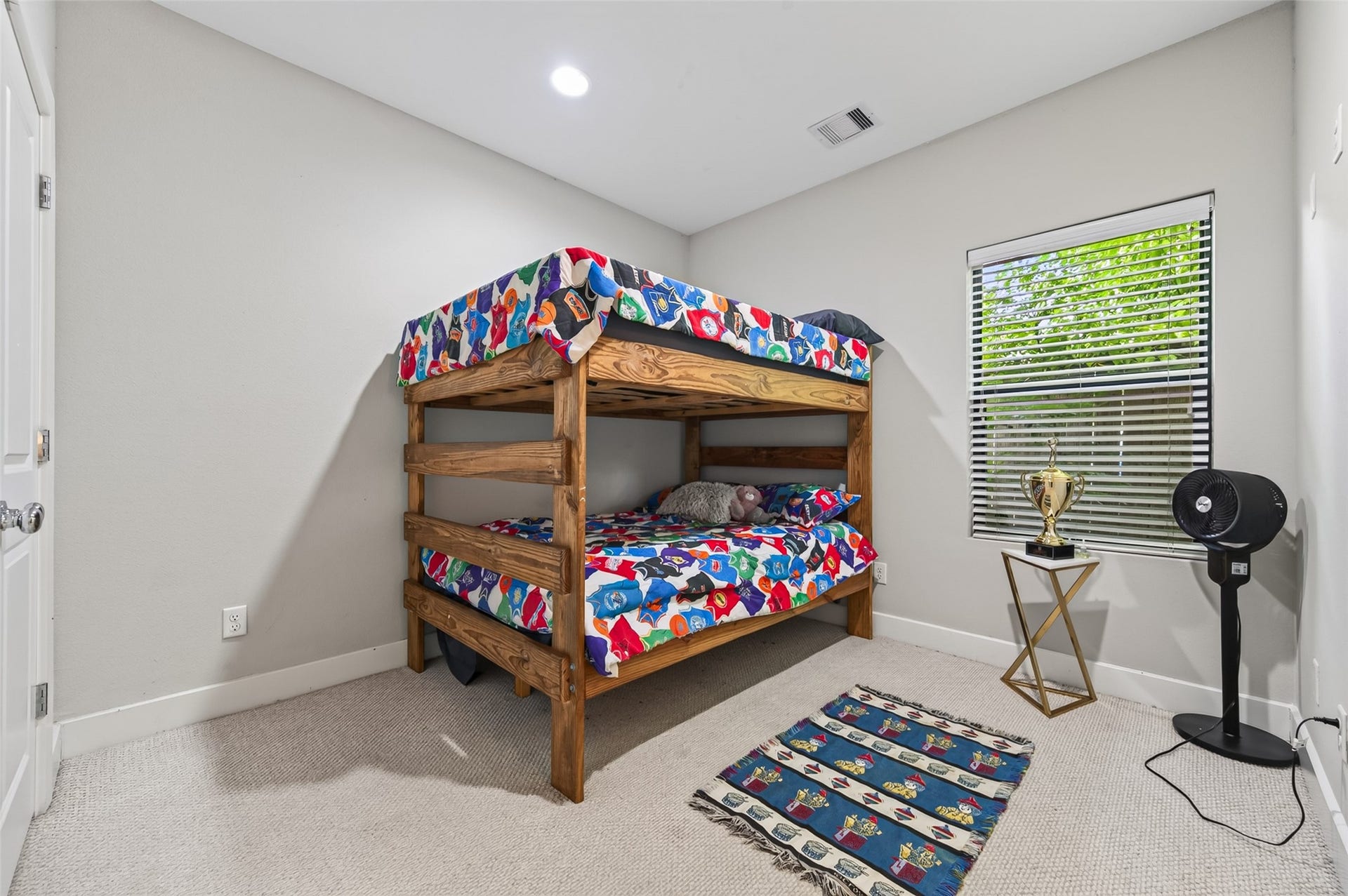 2805 Blodgett Street, #C, Houston, TX 77004 Charming versatile bedroom featuring a cozy wooden bunk bed, colorful decor, and a playful rug. The room is brightened by natural light from a window, complemented by a small play table and storage units.