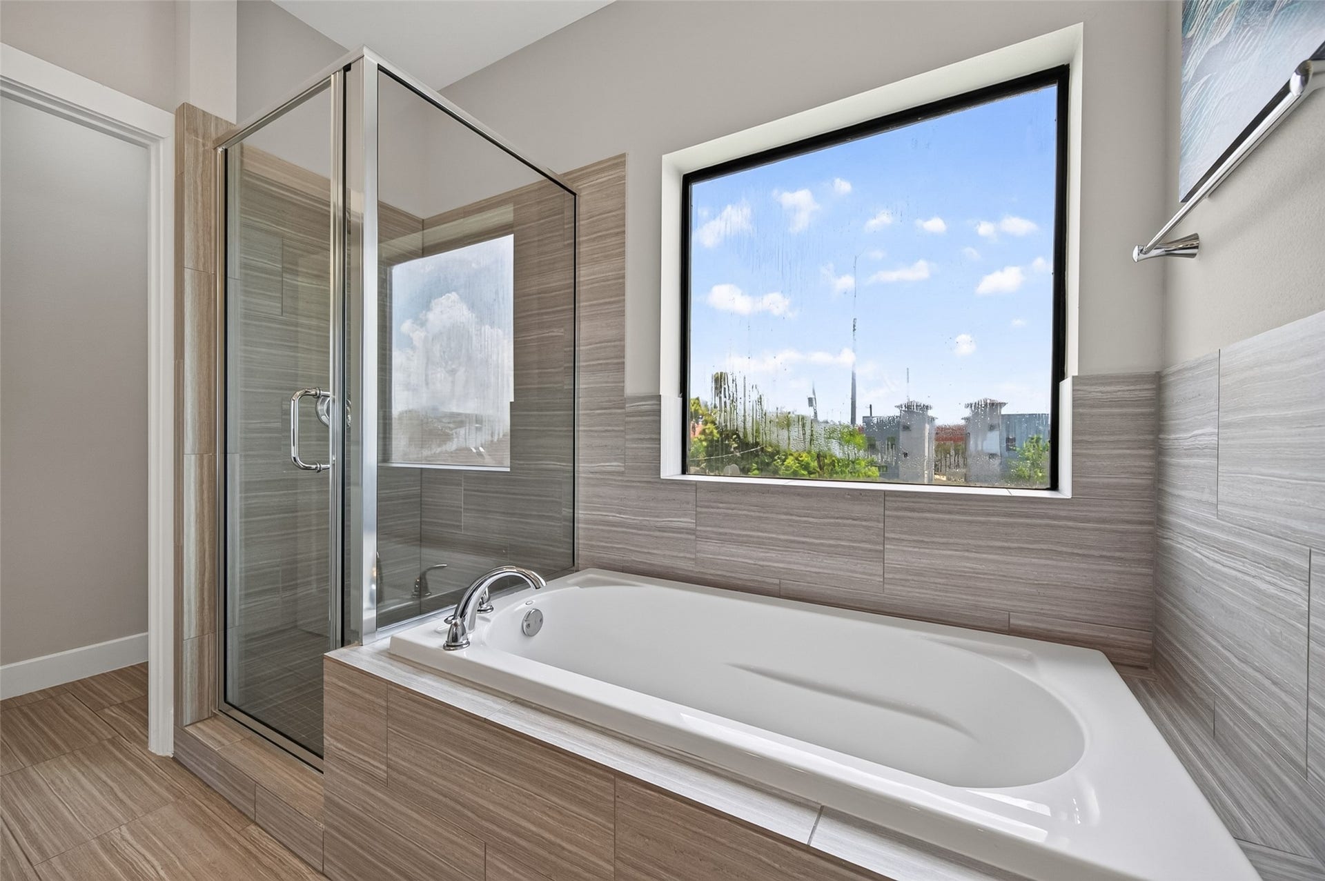 2805 Blodgett Street, #C, Houston, TX 77004 Elegant bathroom featuring a modern soaking tub with sleek fixtures, complemented by stylish tilework and a large window offering natural light and pleasant views.