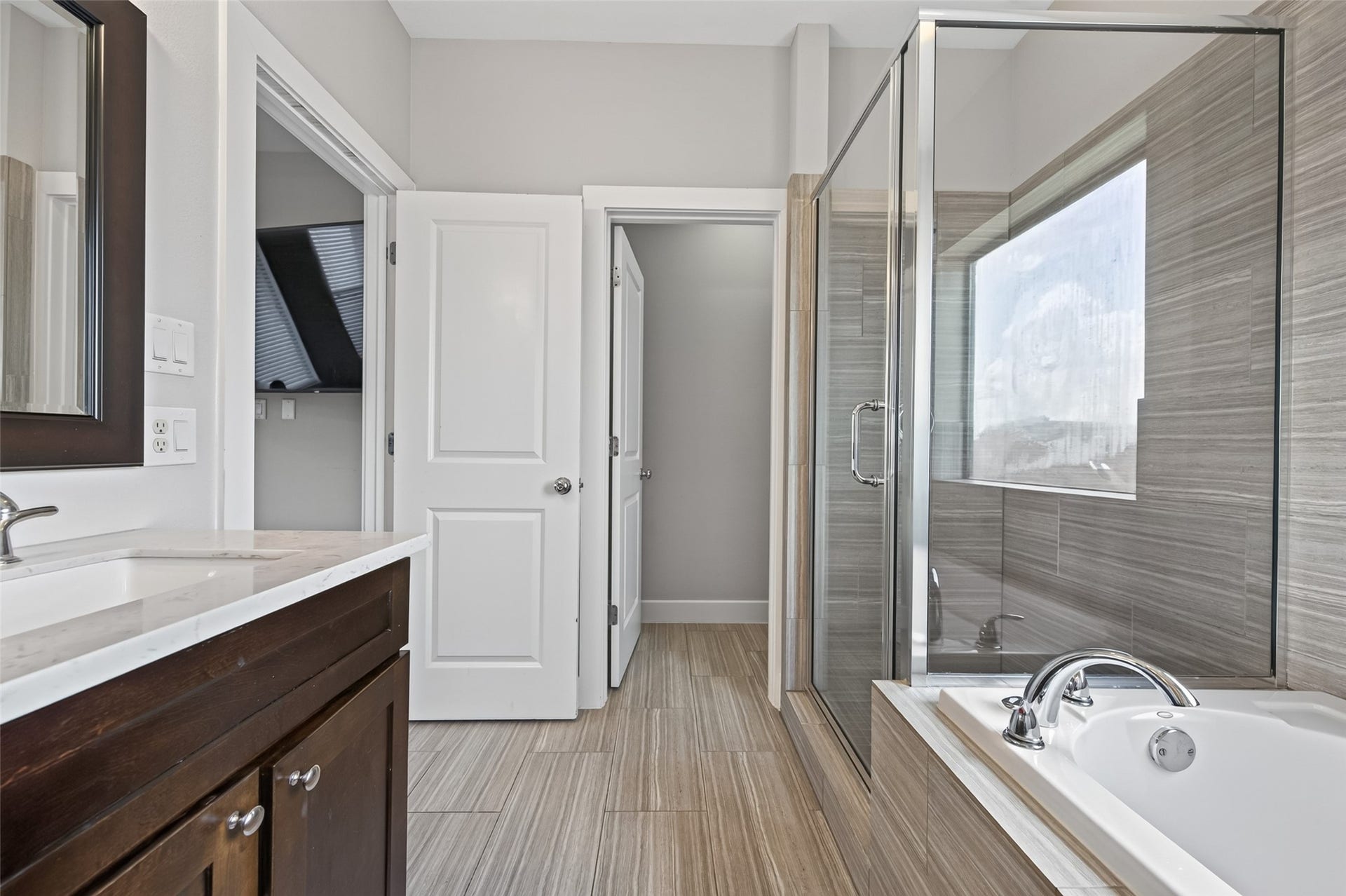 2805 Blodgett Street, #C, Houston, TX 77004 Elegant bathroom featuring a sleek glass-enclosed shower, modern fixtures, and a luxurious bathtub with a large window offering plenty of natural light.