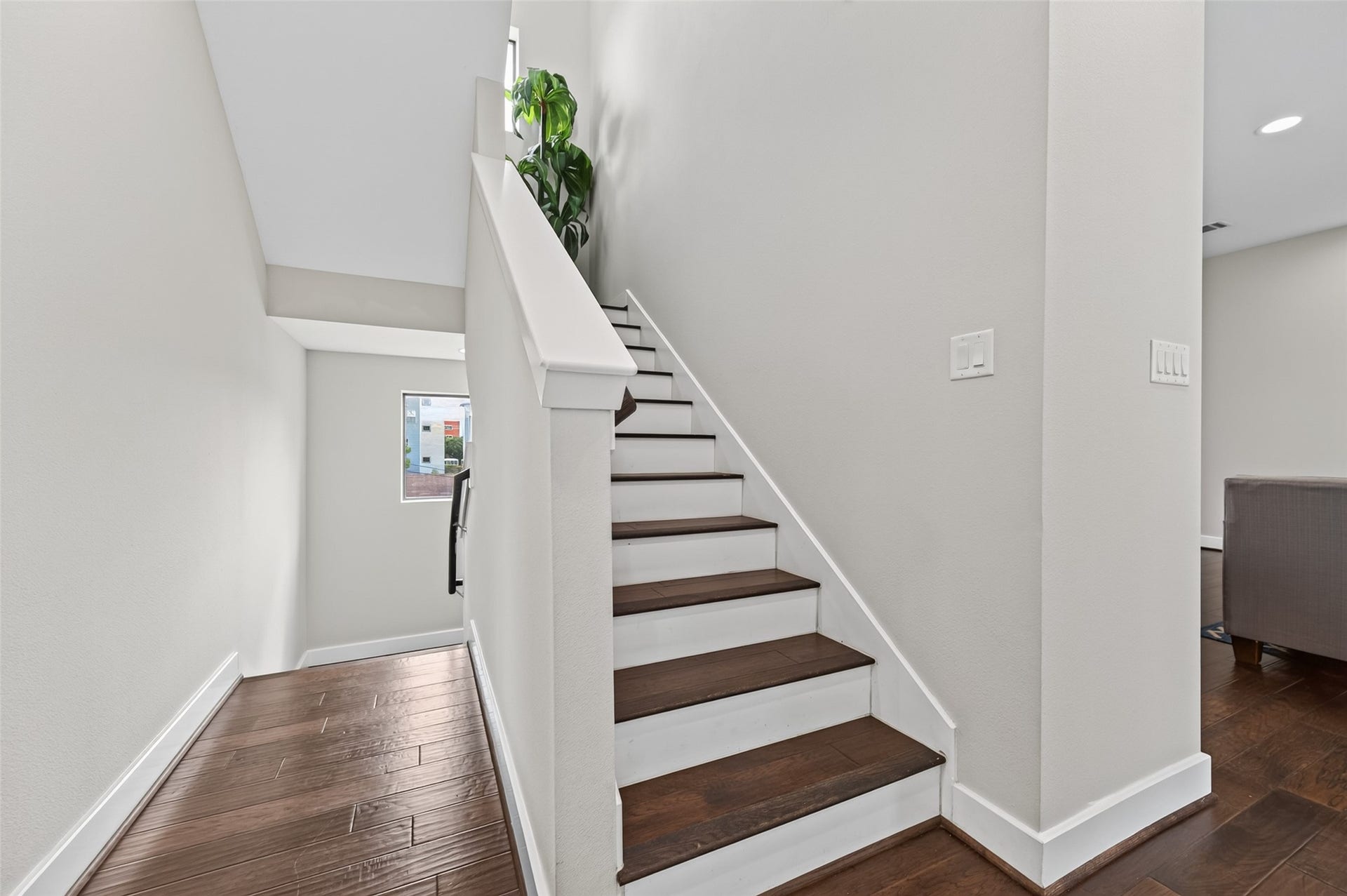 2805 Blodgett Street, #C, Houston, TX 77004 A modern staircase with rich wooden steps leads upward, complemented by crisp white walls and a sleek white door, creating a clean and inviting entryway.
