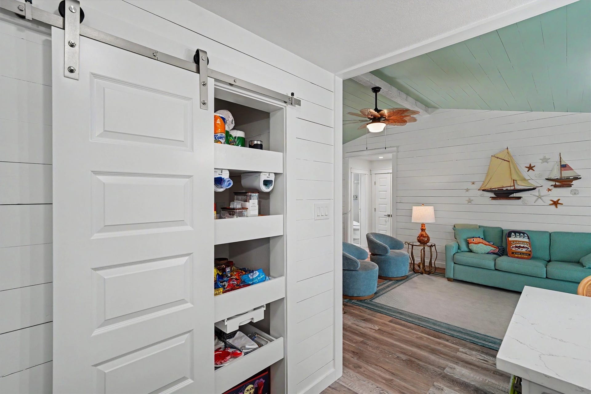 This inviting open-concept layout brings the kitchen and living spaces together beautifully. The updated kitchen maximizes every inch with a pantry featuring convenient pull-out shelving, while modern shiplap walls add texture, character, and a fresh coastal feel