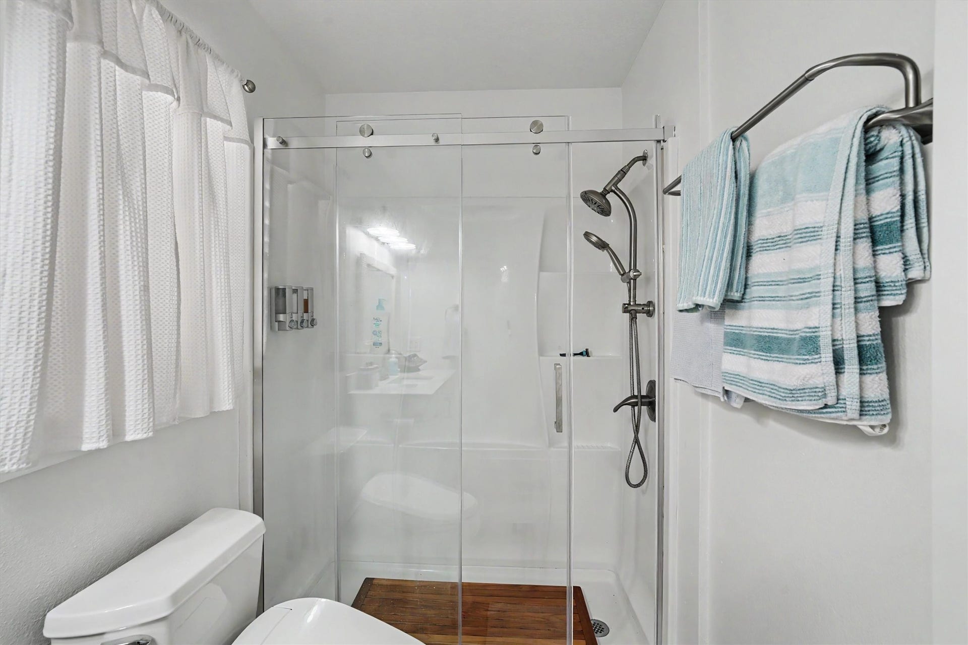 A spacious walk-in shower with a sleek seamless glass door creates a clean, modern retreat.