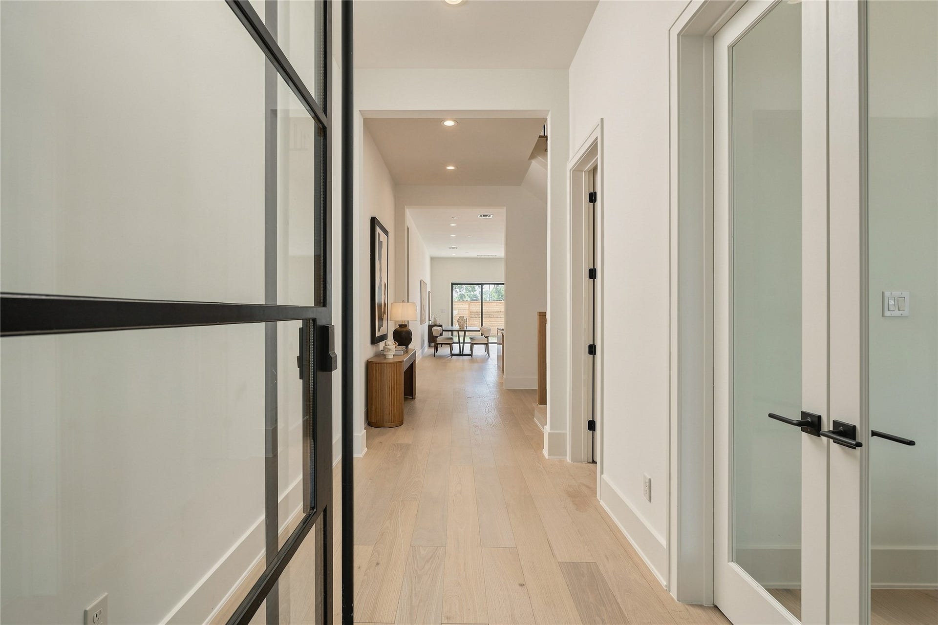 2109 McKean Drive, Houston, TX 77080 A refined entry corridor sets the tone with engineered oak hardwood flooring, 8-foot solid-core doors, and contrasting black hardware, offering a clean, architectural introduction to the home.