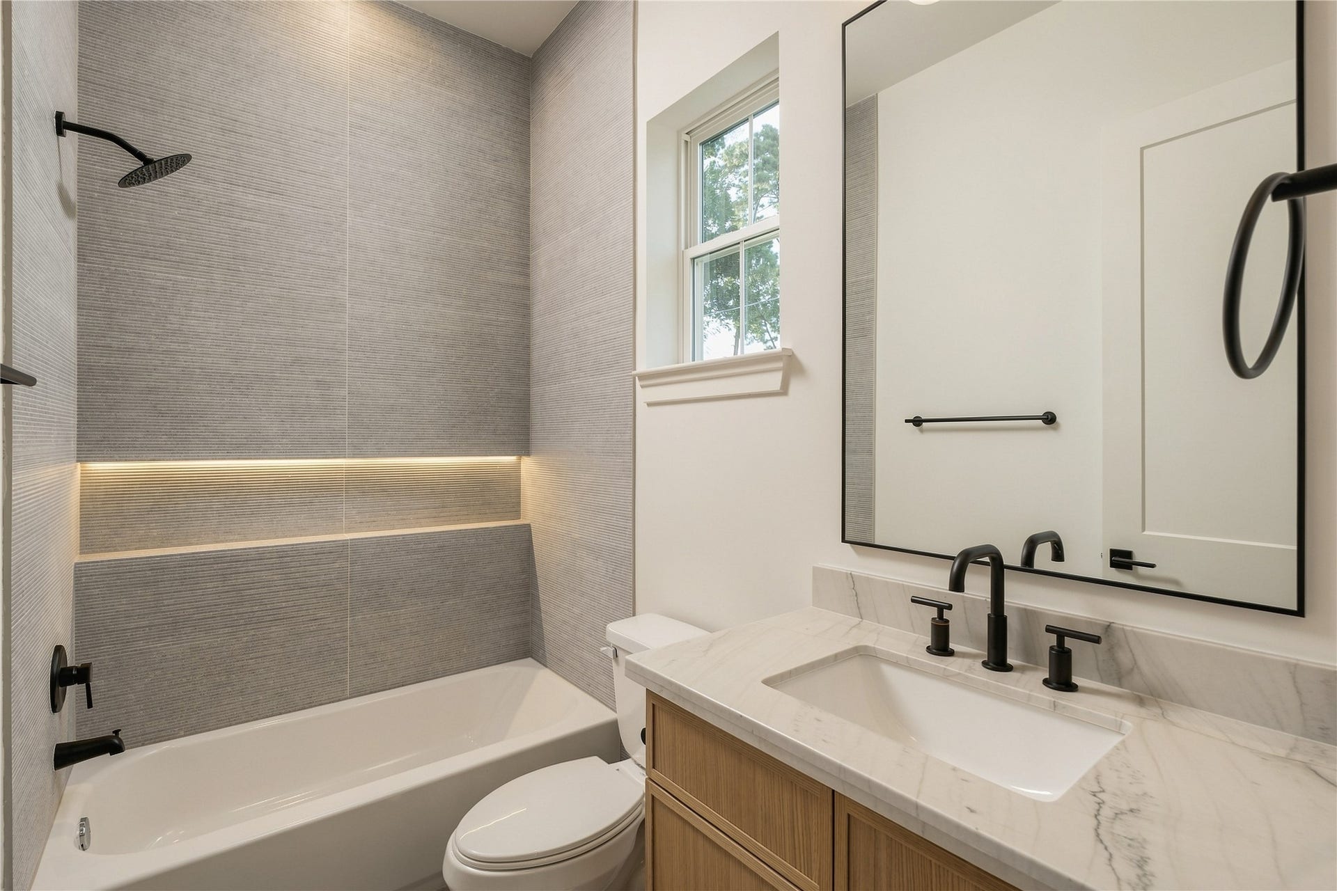 2109 McKean Drive, Houston, TX 77080 A well-appointed secondary bath features a frameless glass shower, full-height designer tile, and an illuminated shower niche, continuing the homes attention to detail across every ensuite.