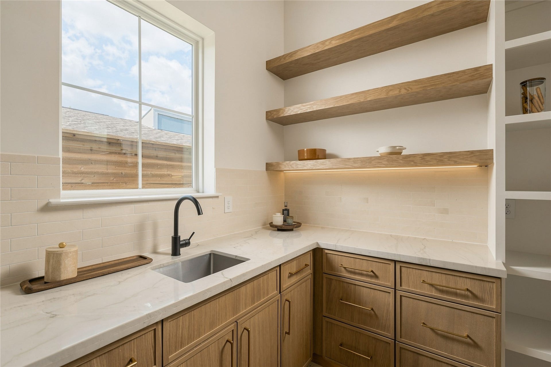 2109 McKean Drive, Houston, TX 77080 A discreet scullery-style pantry extends the kitchens functionality with generous prep space, additional cabinetry, open white oak shelving, and its own sinkkeeping the main kitchen ready for entertaining.