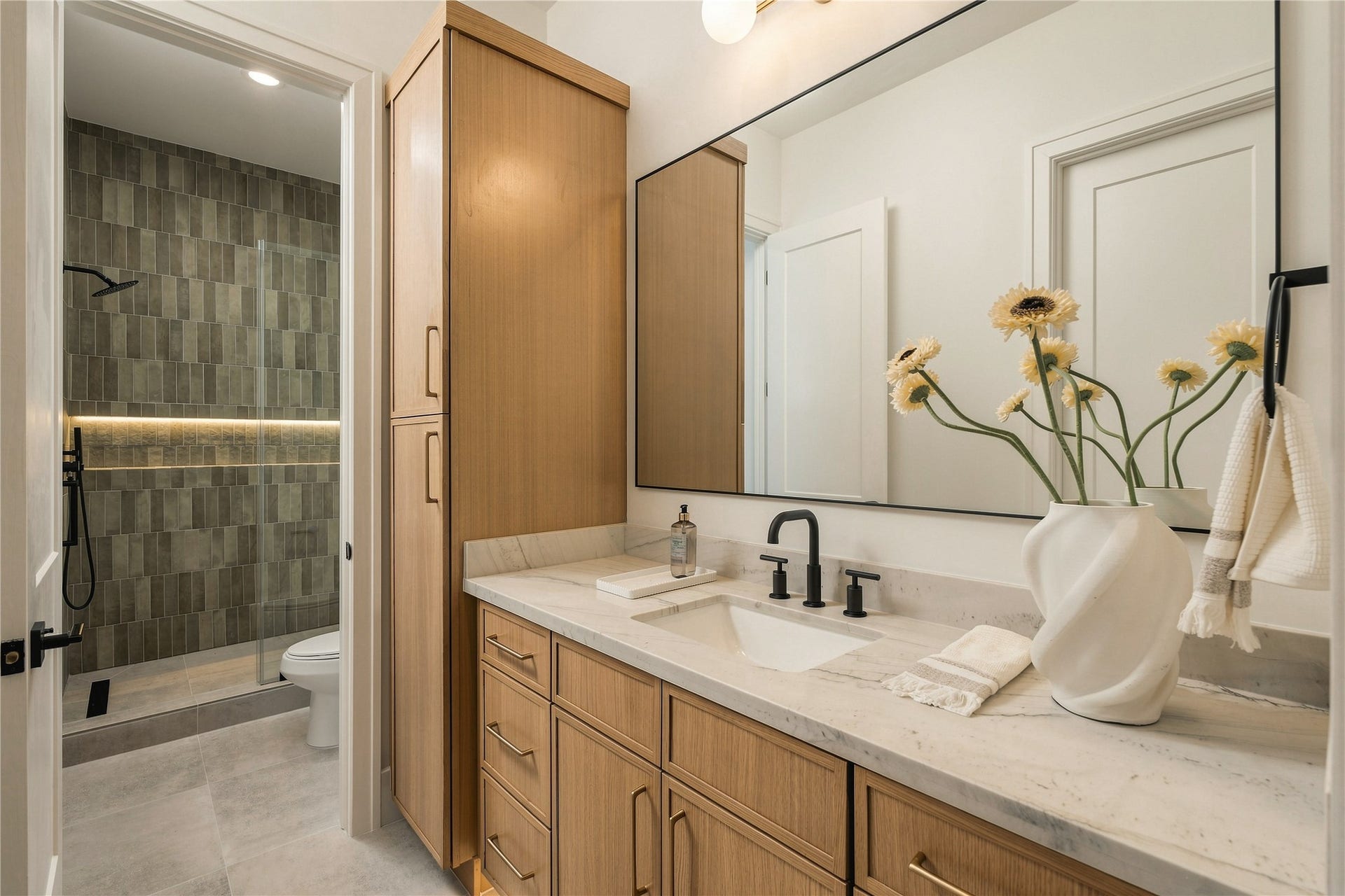 2109 McKean Drive, Houston, TX 77080 The secondary bath is finished with Mount Blanc Quartzite countertops, full-height designer tile, and a frameless glass shower, bringing the same level of finish found throughout the home into the guest accommodations.