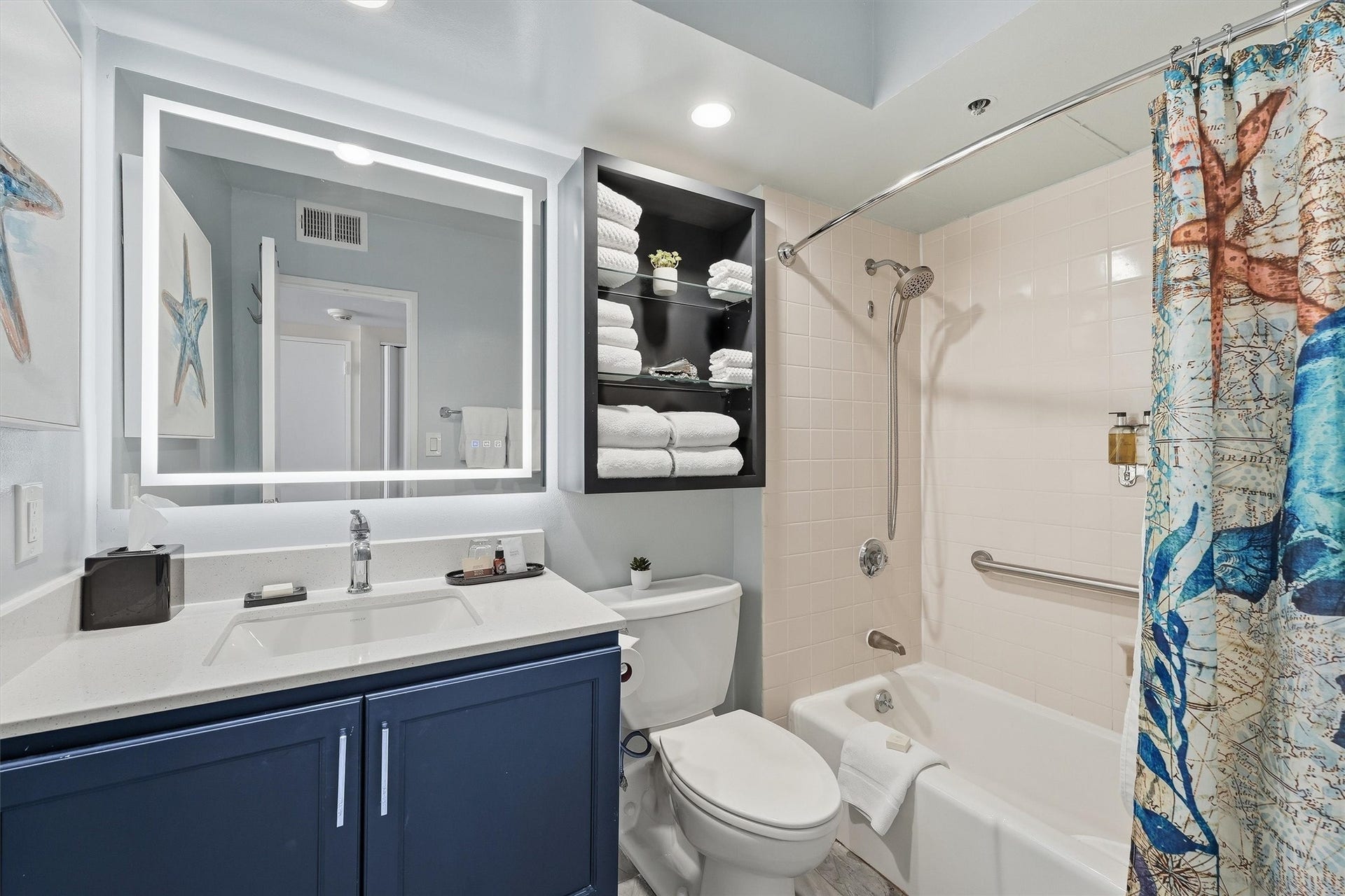 5220 Seawall Boulevard, #1038B, Galveston, TX 77551 The bathroom features a navy vanity, illuminated mirror, and a convenient tub/shower combination.