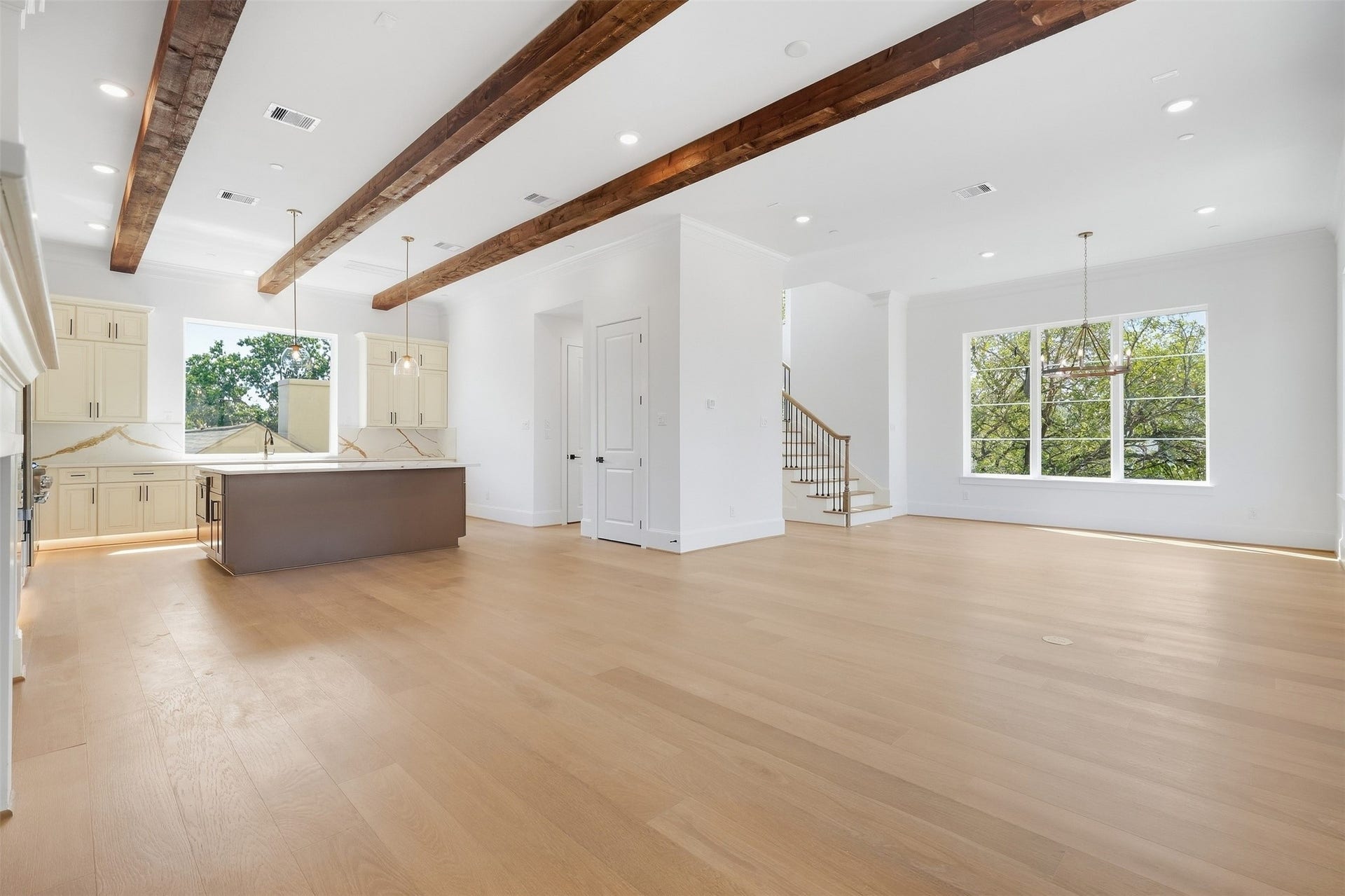 2111 Nantucket Drive, #D, Houston, TX 77057 A wide view of the open-concept living, dining, and kitchen areas showcases the generous scale, natural light, wide plank flooring, and exposed wood beams throughout.