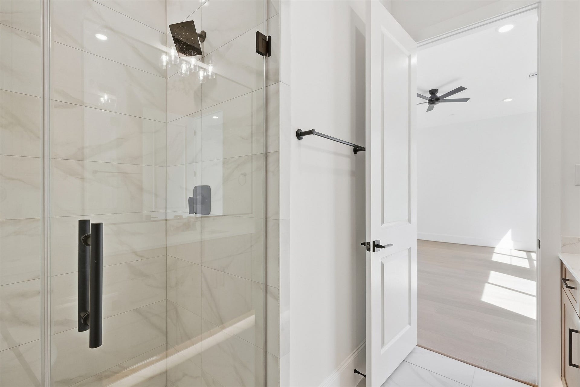 2111 Nantucket Drive, #D, Houston, TX 77057 The first-floor full bath features a glass-enclosed walk-in shower with floor to ceiling tile, rainfall showerhead, and matte black fixtures.