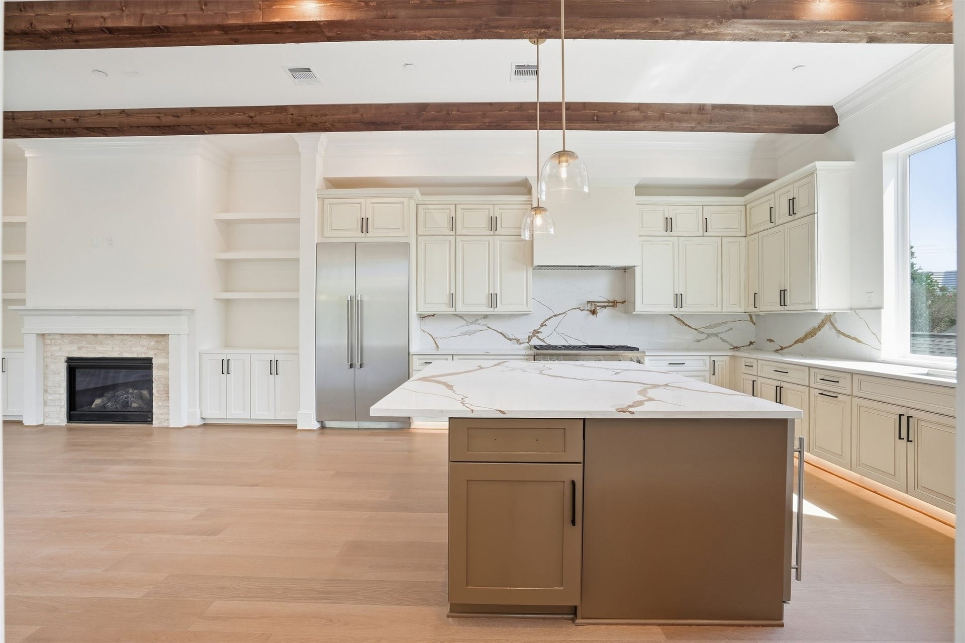 2111 Nantucket Drive, #D, Houston, TX 77057 The kitchen opens directly to the living area, creating a seamless space for everyday living and entertaining, with an oversized island, fireplace, built-ins, and warm exposed wood beams.