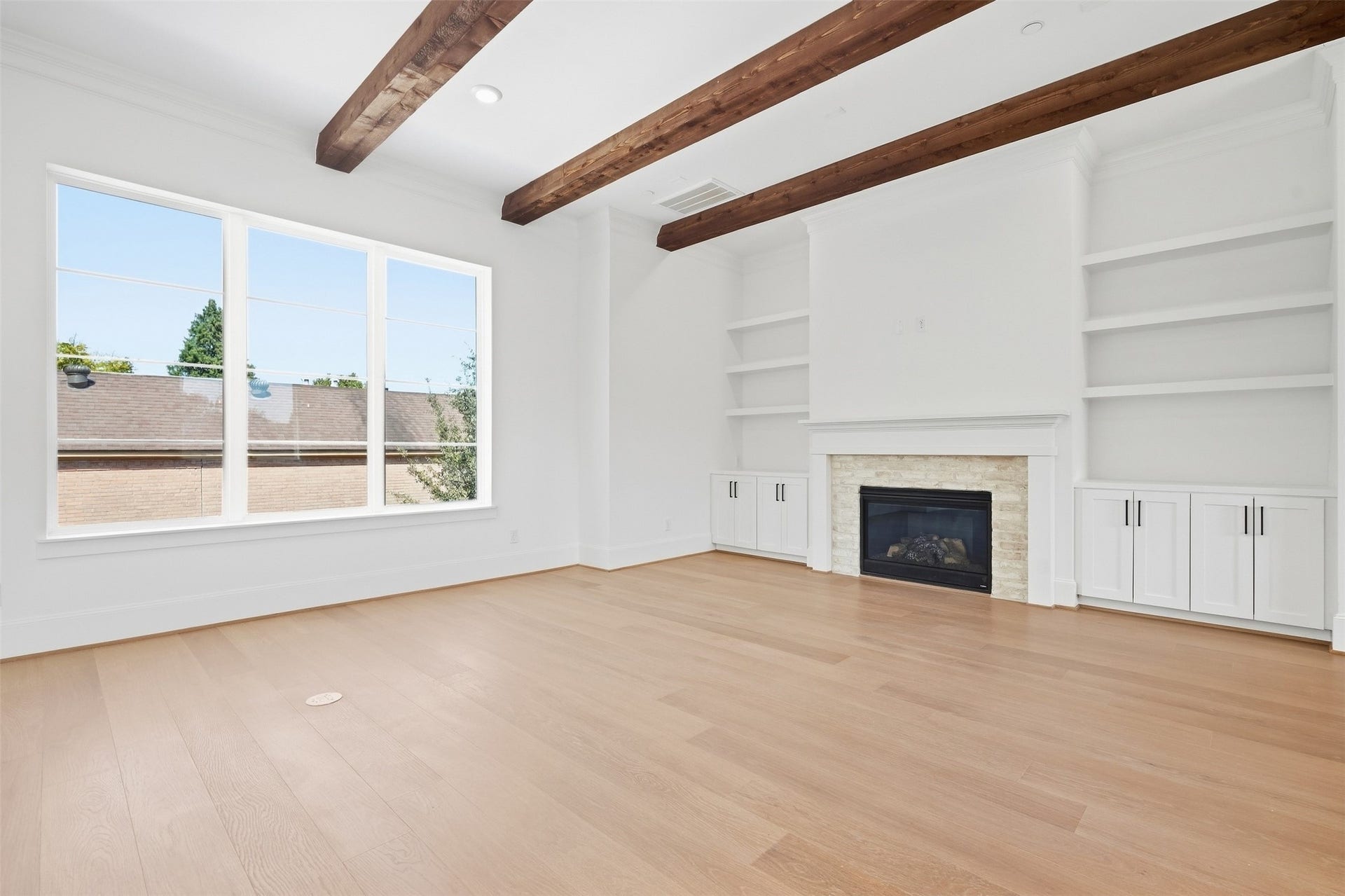 2111 Nantucket Drive, #D, Houston, TX 77057 Expansive windows fill the living area with natural light, while real cedar ceiling beams and a fireplace create a warm, inviting focal point.