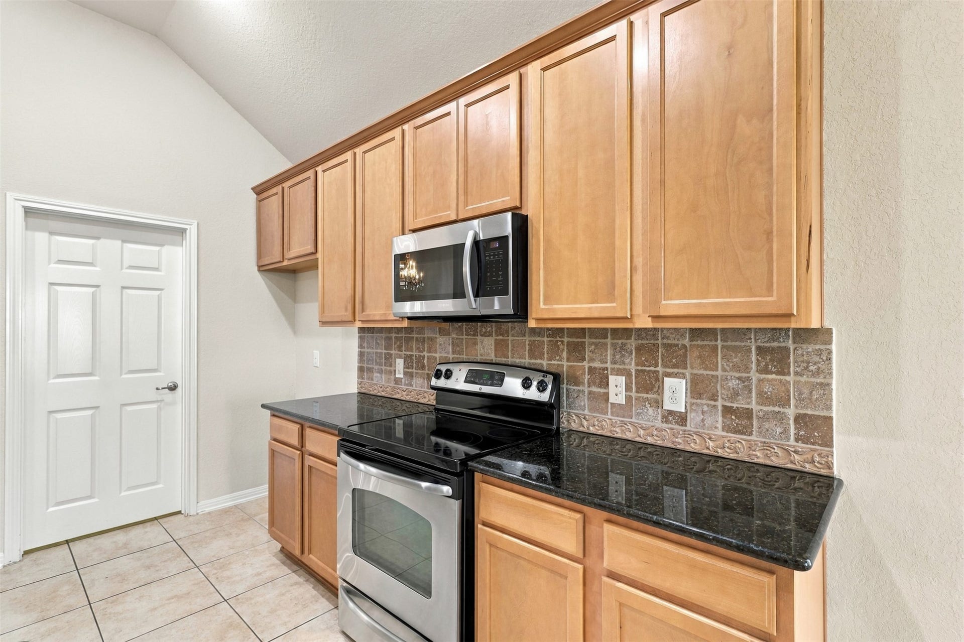 6414 Pinyon Trail Drive, Spring, TX 77389 Another view of the kitchen with sleek black granite countertops, stainless steel appliances, and ample light wood cabinetry for storage.