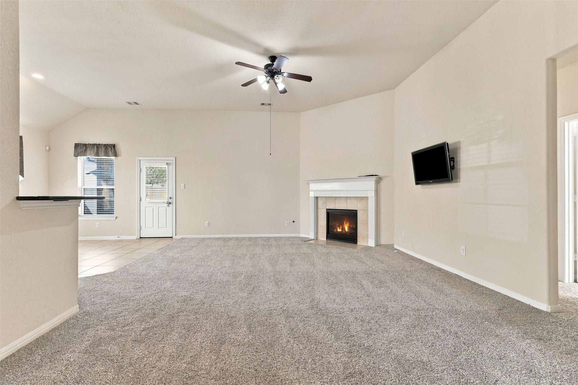 6414 Pinyon Trail Drive, Spring, TX 77389 Spacious living room with a cozy fireplace, plush new carpeting (2026), and a ceiling fan, offering a warm and inviting atmosphere.