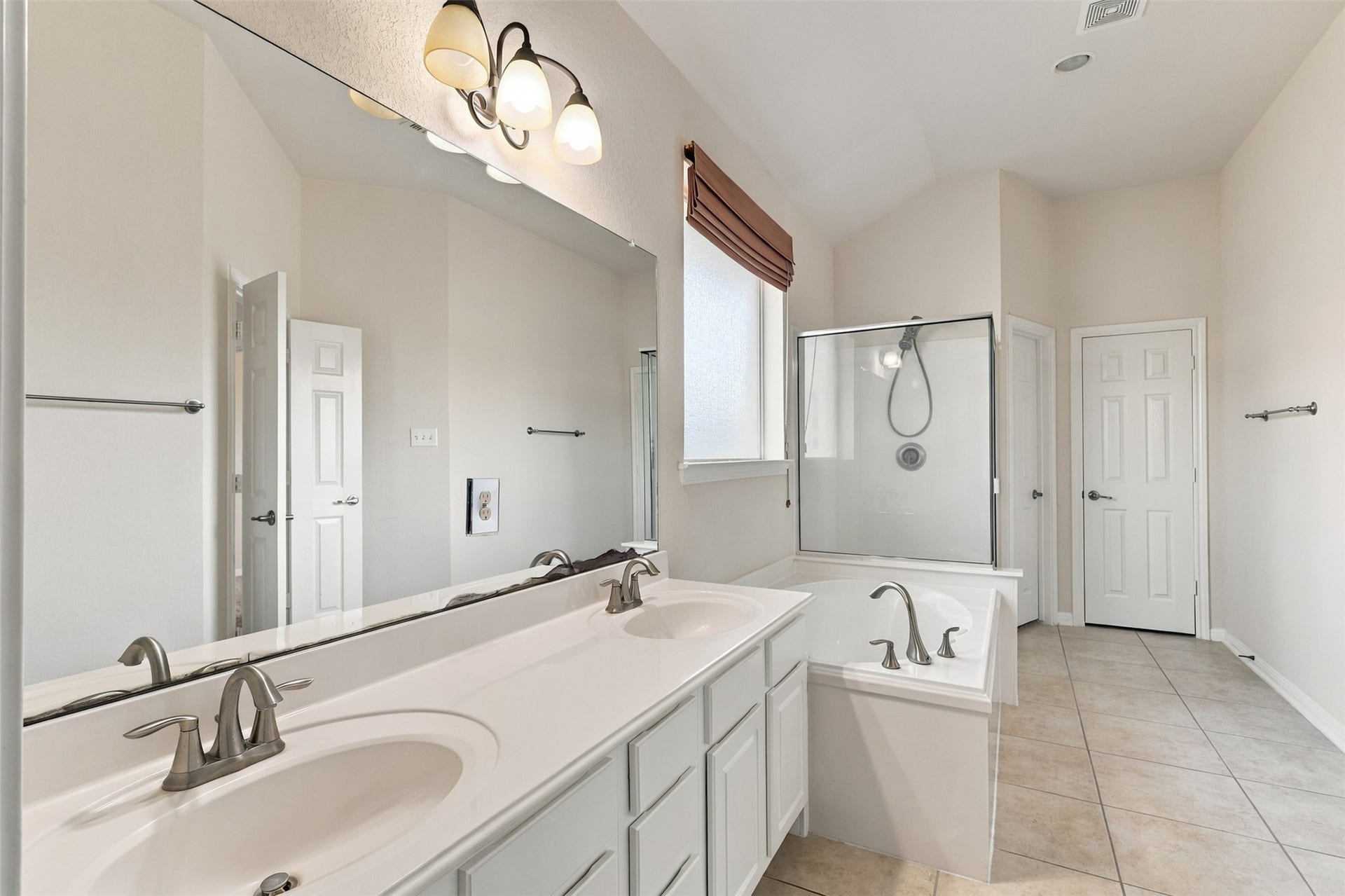6414 Pinyon Trail Drive, Spring, TX 77389 Bright bathroom featuring a double vanity, large mirror, and elegant fixtures, complemented by a separate glass-enclosed shower and soaking tub.