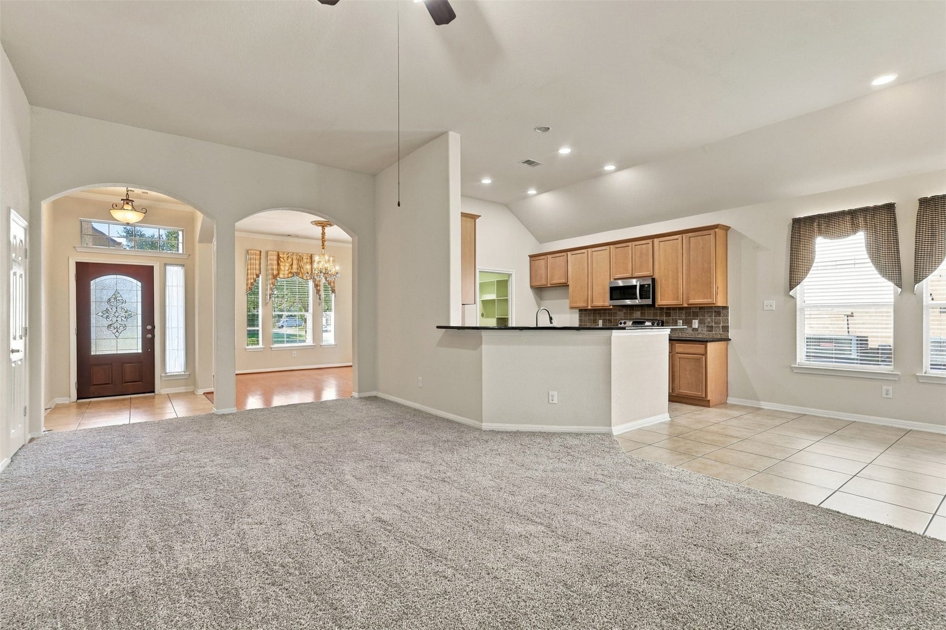 6414 Pinyon Trail Drive, Spring, TX 77389 Spacious open-concept living area with plush carpeting, high ceilings, and abundant natural light, seamlessly connecting to a modern kitchen with ample cabinetry and a cozy breakfast bar.