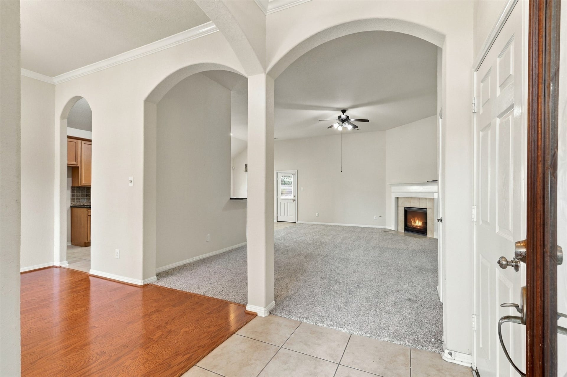 6414 Pinyon Trail Drive, Spring, TX 77389 Inviting open-concept living area featuring arched doorways, a cozy fireplace, and a mix of tile and hardwood flooring, creating a warm and welcoming atmosphere.