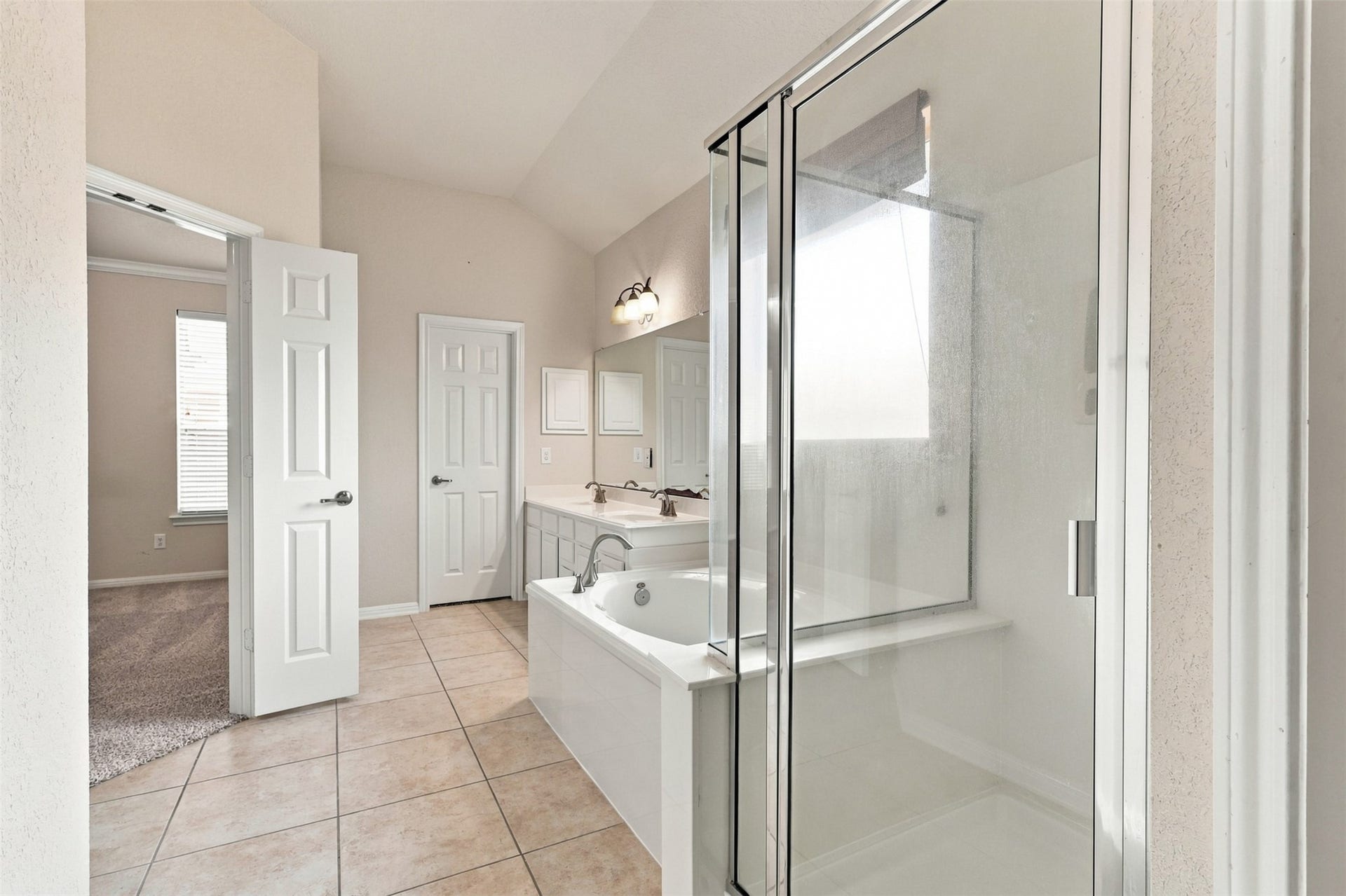 6414 Pinyon Trail Drive, Spring, TX 77389 Elegant bathroom featuring a spacious glass-enclosed shower and a relaxing bathtub, complemented by dual sinks and ample natural light.