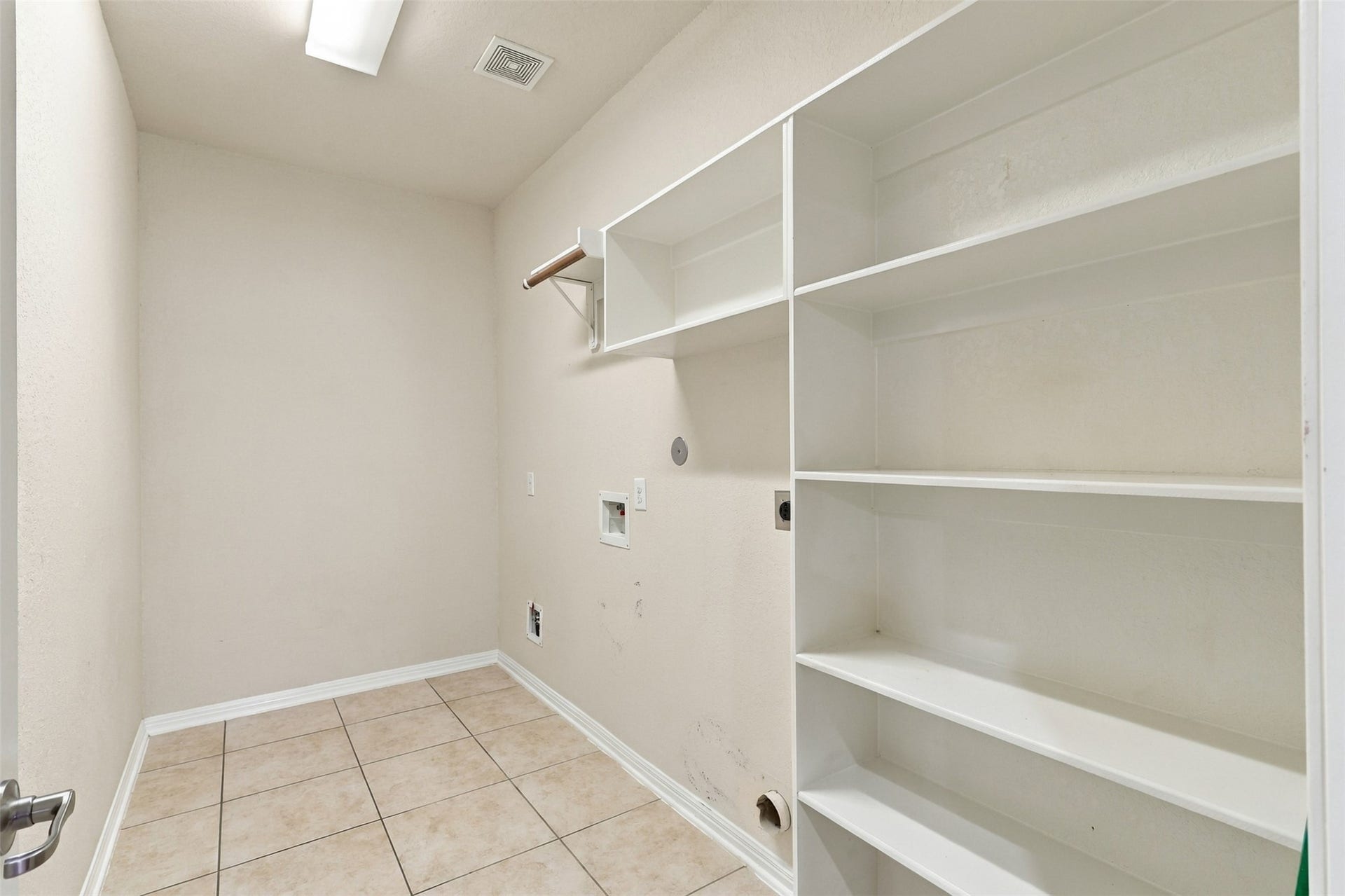 6414 Pinyon Trail Drive, Spring, TX 77389 Spacious laundry room with built-in shelving and tile flooring, offering ample storage and functionality.