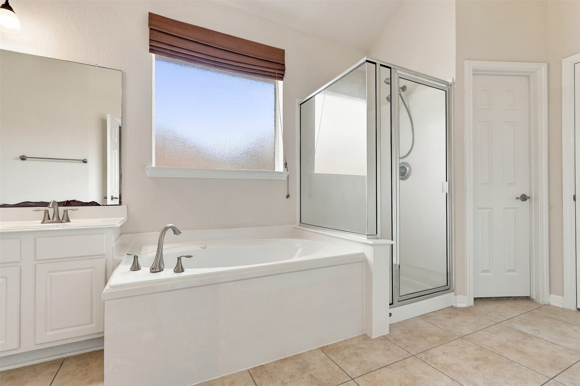 6414 Pinyon Trail Drive, Spring, TX 77389 Spacious bathroom featuring a modern glass-enclosed shower, a large soaking tub, and elegant tile flooring.