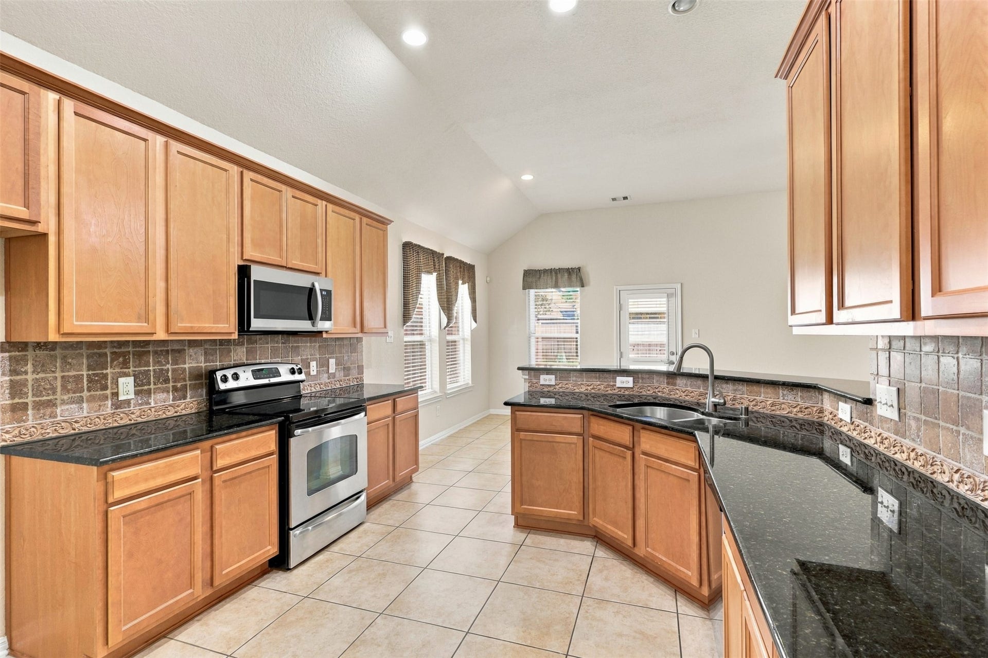 6414 Pinyon Trail Drive, Spring, TX 77389 This kitchen features sleek granite countertops, stainless steel appliances, and warm wood cabinetry, complemented by a stylish tile backsplash and ample natural light.