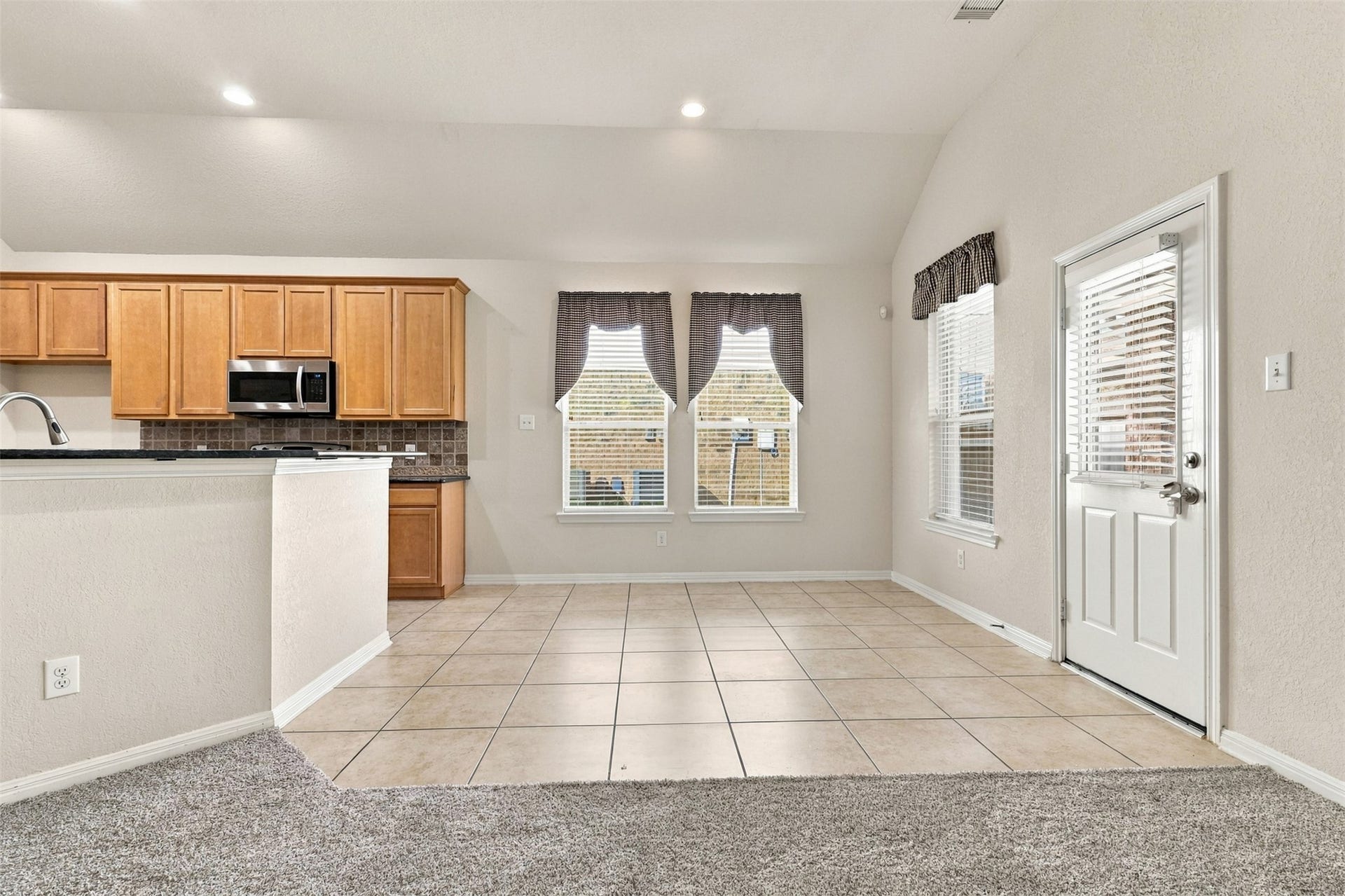 6414 Pinyon Trail Drive, Spring, TX 77389 Bright open concept kitchen and dining area with natural light, featuring wood cabinetry, modern appliances, and a convenient tile floor layout.