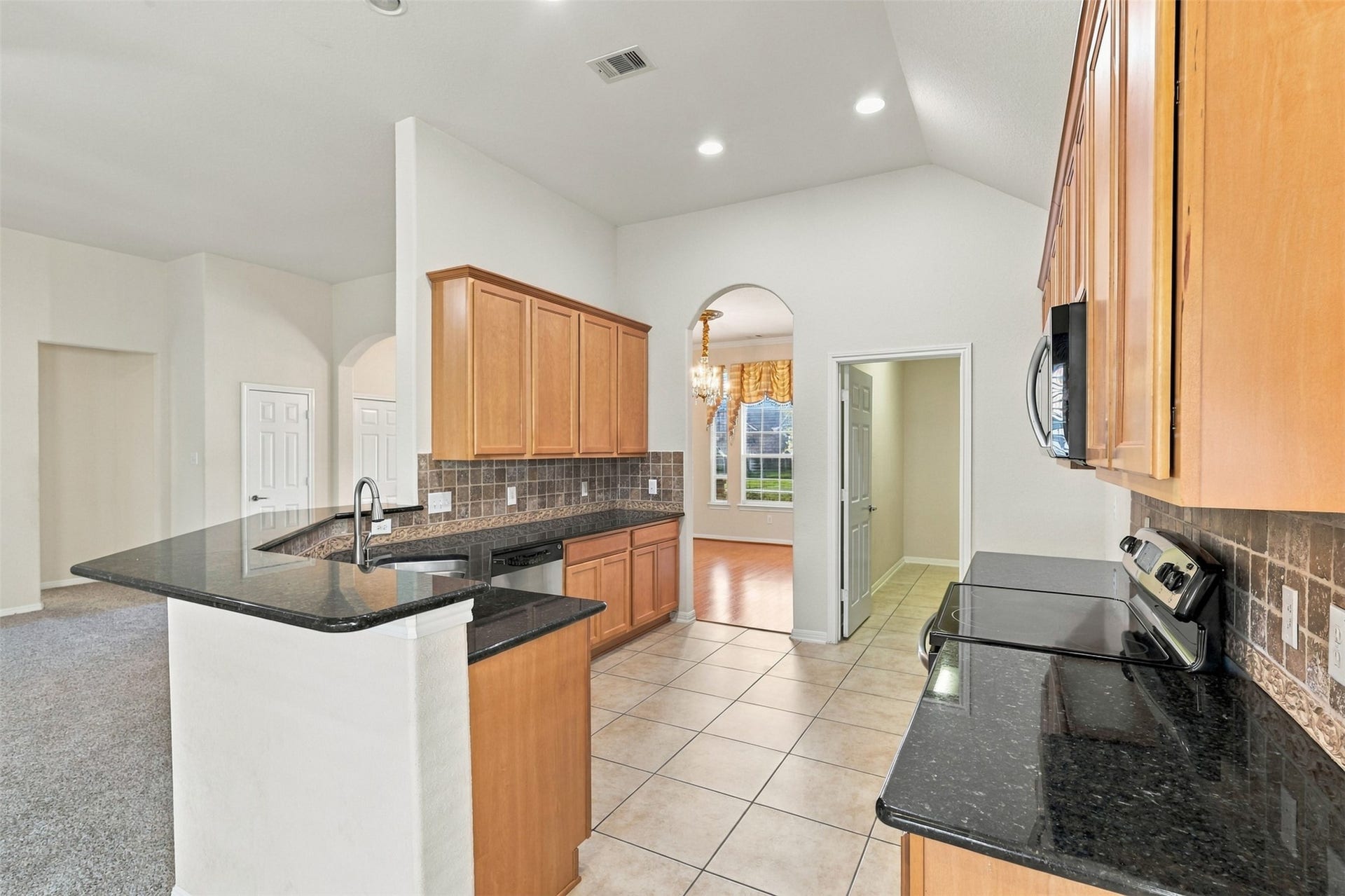 6414 Pinyon Trail Drive, Spring, TX 77389 Modern kitchen with sleek granite countertops, ample cabinetry, and stainless steel appliances, seamlessly flowing into a spacious, light-filled dining area.