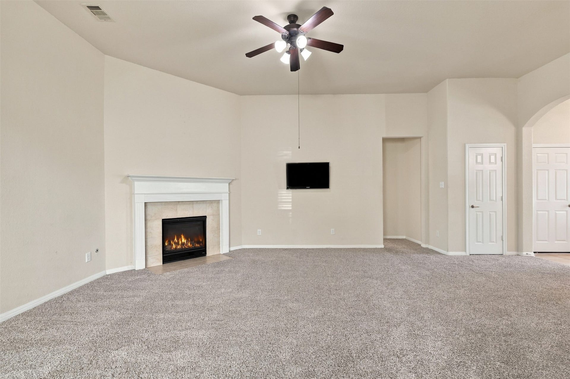 6414 Pinyon Trail Drive, Spring, TX 77389 Spacious living room with plush carpet, featuring a cozy fireplace and ceiling fan, perfect for relaxation and entertainment.
