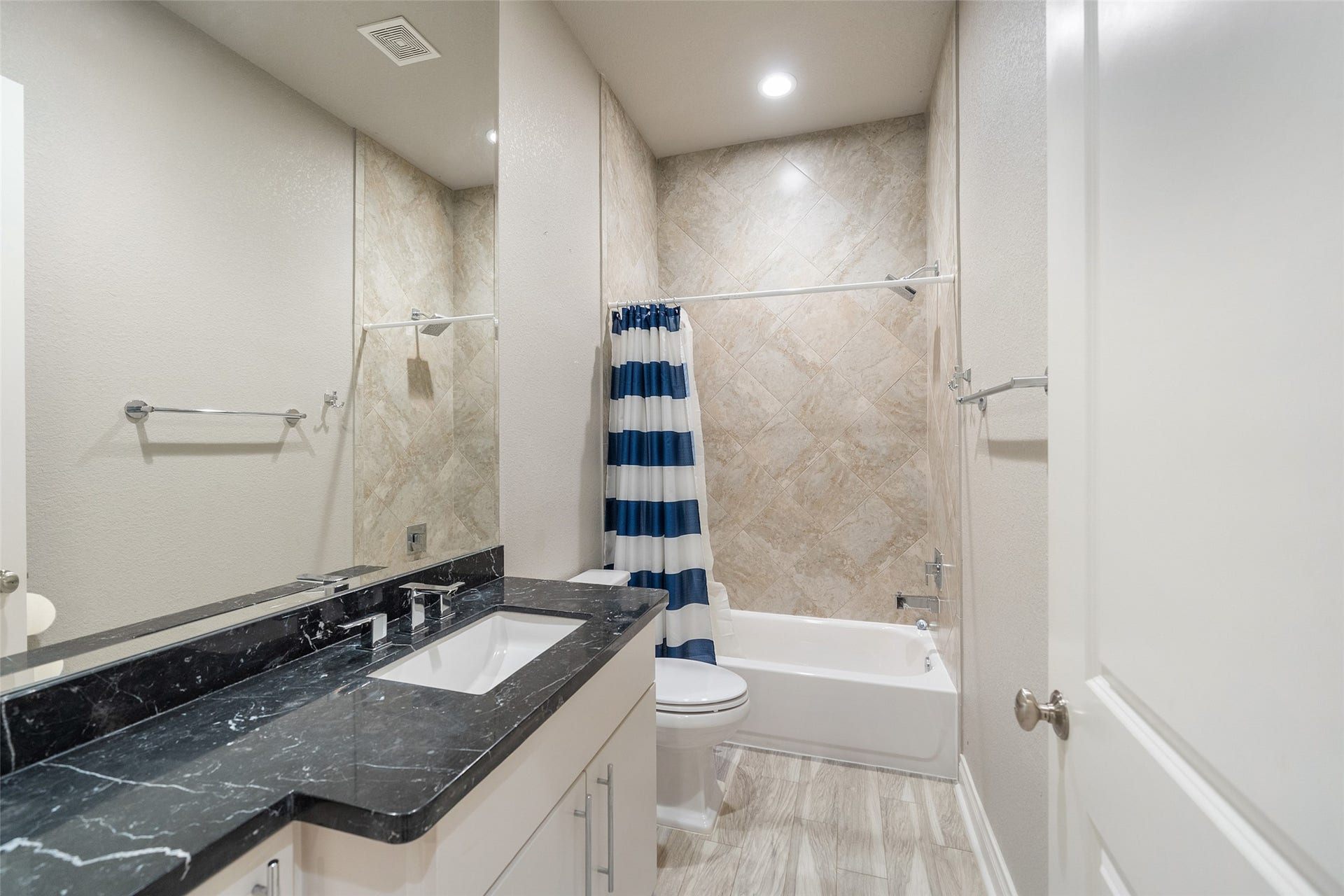 Guest full bath with marble counters and tub/shower combo.