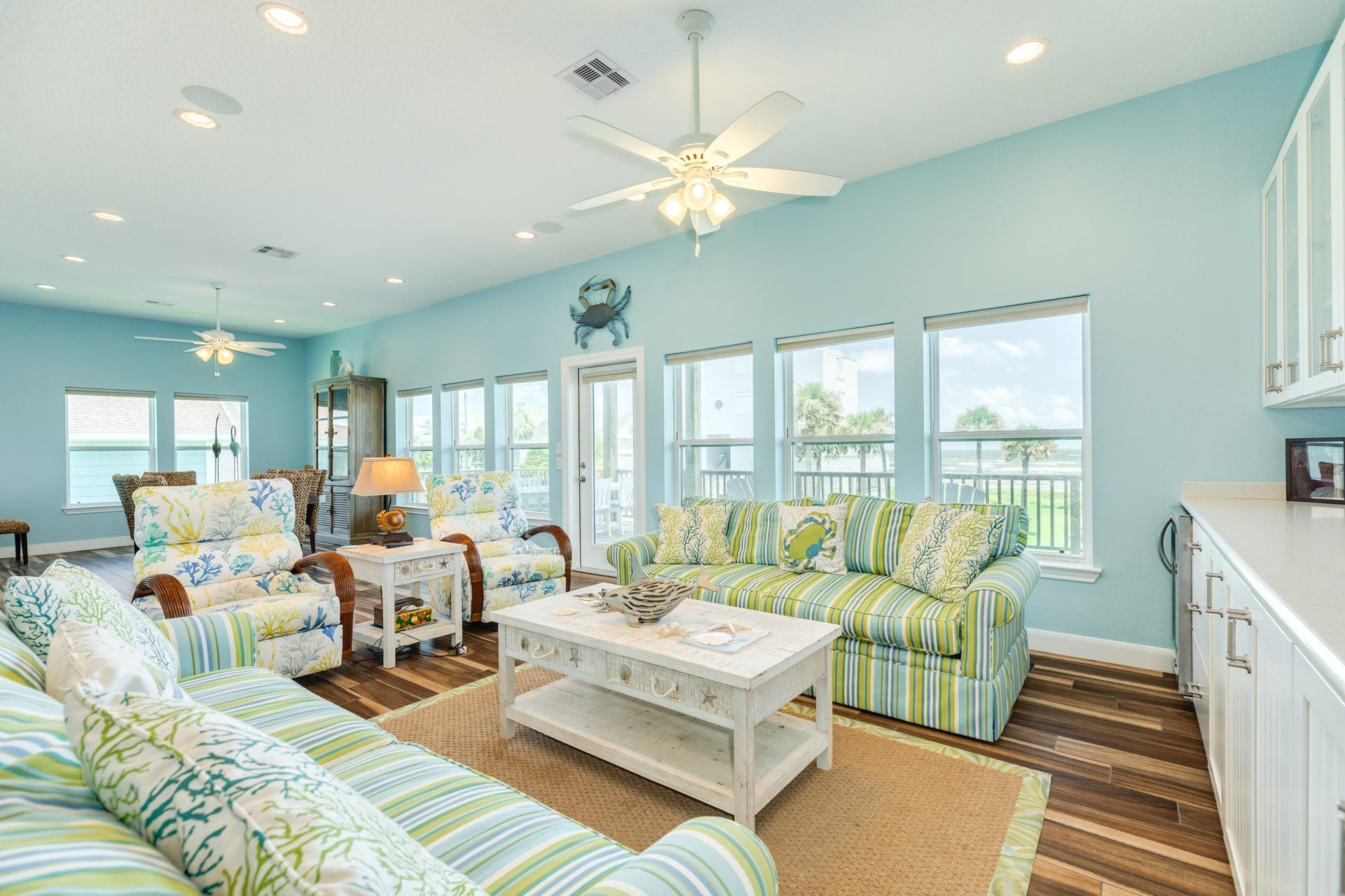 18502 E De Vaca, Galveston, TX 77554 Window placement provides an abundance of natural light. The console on the wall behind the couches has storage both up and down in addition to a beveridge fridge.