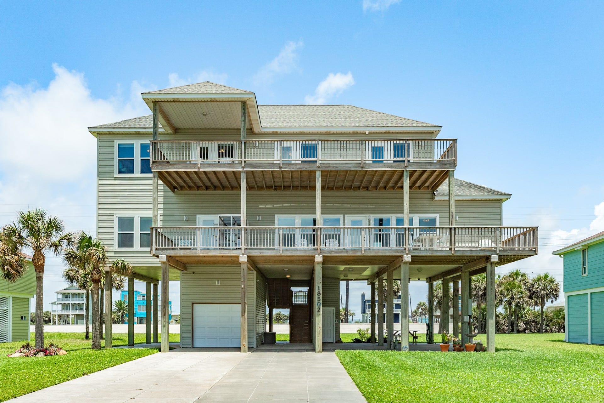 18502 E De Vaca, Galveston, TX 77554 South elevation of home. Spacious decks on each level of the home, 1 car attached garage, large paved patios underr home and elevator access on the ground floor.