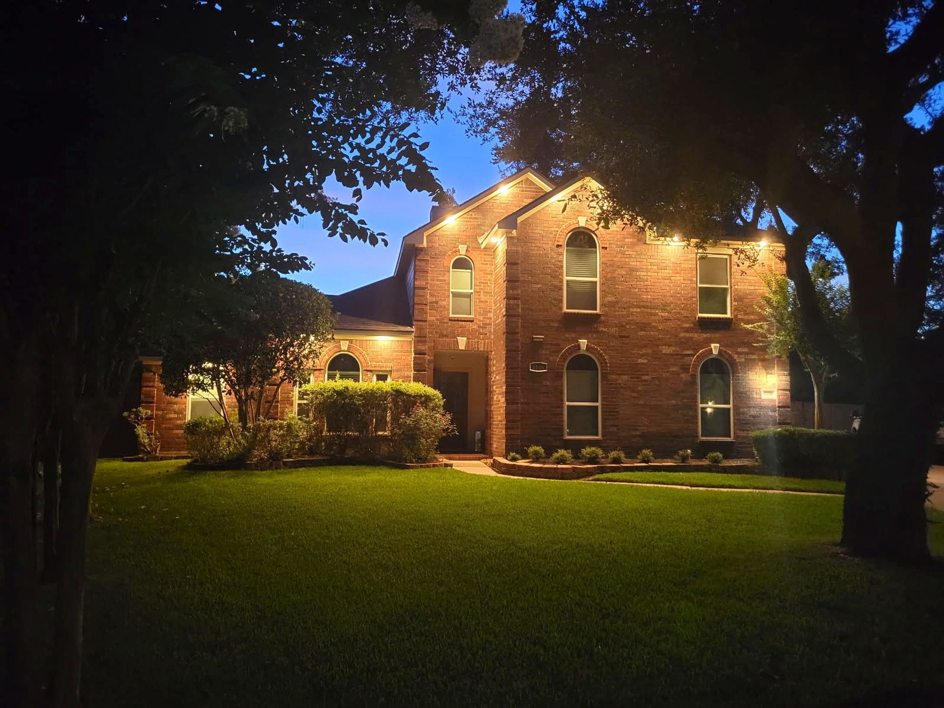 1806 Kensington Park Circle, Spring, TX 77386 Elegant exterior lighting accents the brick facade and rooflines at dusk.
