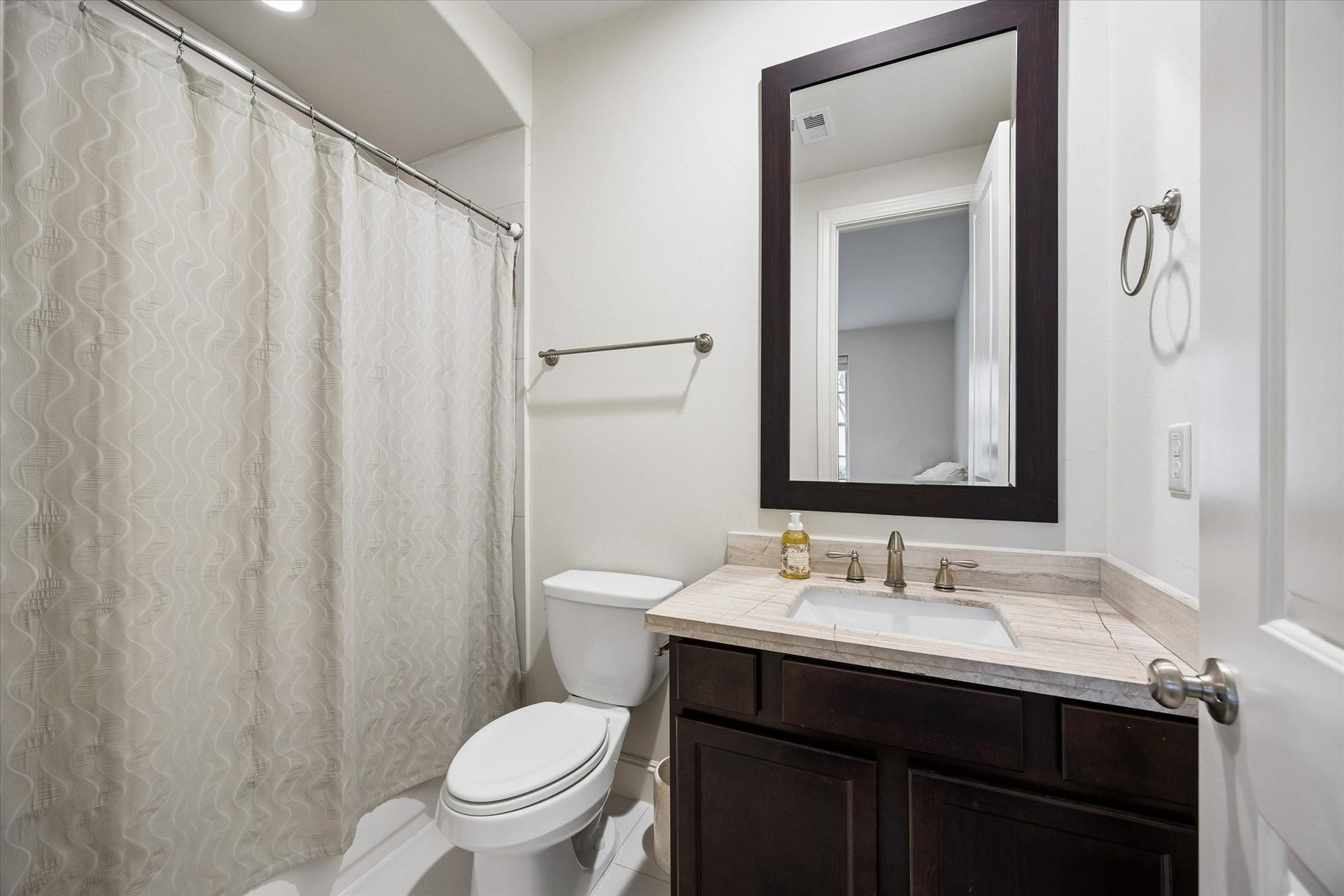 2725 Cohn Garden, Houston, TX 77007 En suite bath for the first floor bedroom provides added privacy and convenience, complete with a tub and shower combination, stone topped vanity, and dark wood cabinetry.