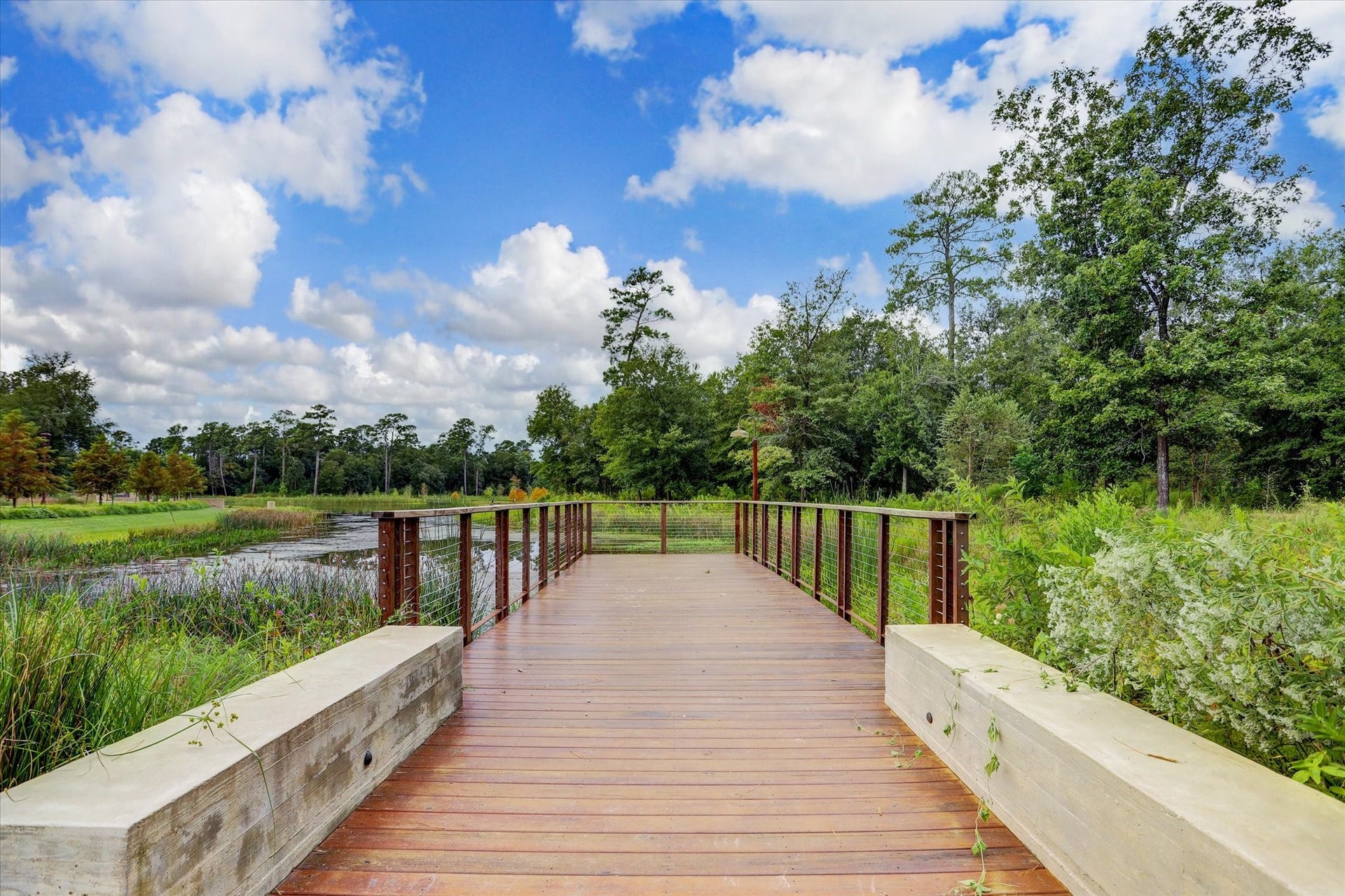 2725 Cohn Garden, Houston, TX 77007 Wooden pedestrian bridge overlooking preserved green space and water features, offering a peaceful connection to miles of nearby walking trails.