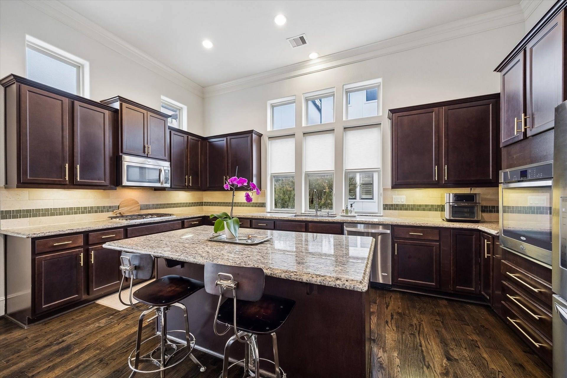 2725 Cohn Garden, Houston, TX 77007 Granite countertops wrap the spacious kitchen, pairing with rich wood cabinetry, stainless steel appliances, and under cabinet lighting. A large center island adds additional prep space and seating, while windows above the sink bring in natural light.
