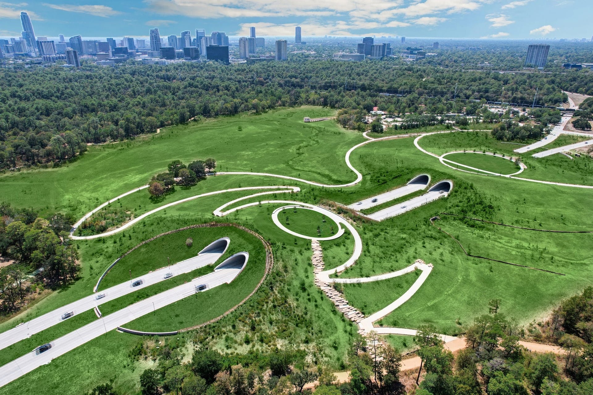 2725 Cohn Garden, Houston, TX 77007 Aerial view of Memorial Parks Land Bridge, connecting miles of hike and bike trails across 100 acres of preserved green space, with downtown Houston skyline in the distance.