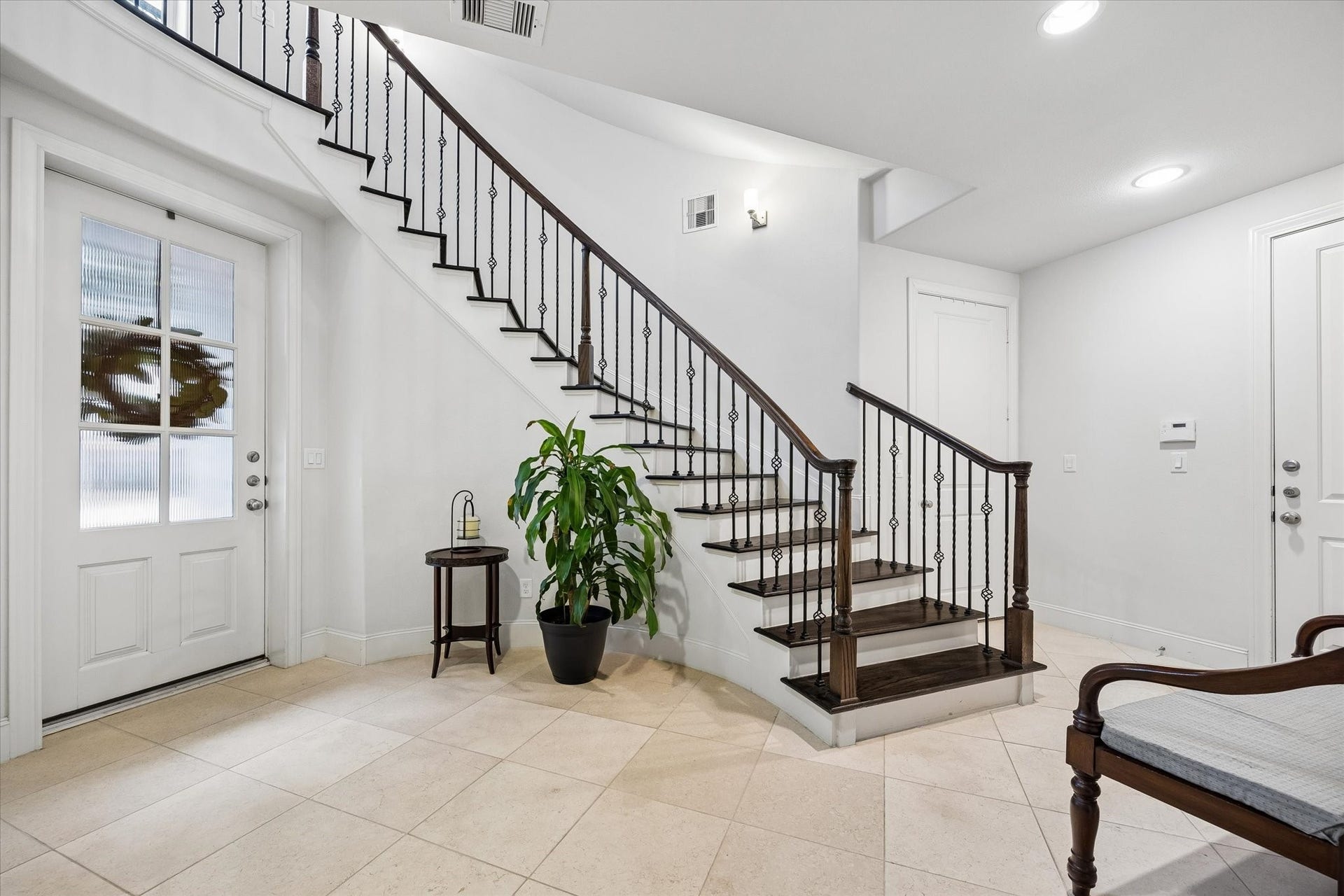 2725 Cohn Garden, Houston, TX 77007 A graceful staircase with dark wood treads and wrought iron detailing creates an architectural focal point upon entry. Light stone floors and bright white walls keep the foyer feeling open and polished.